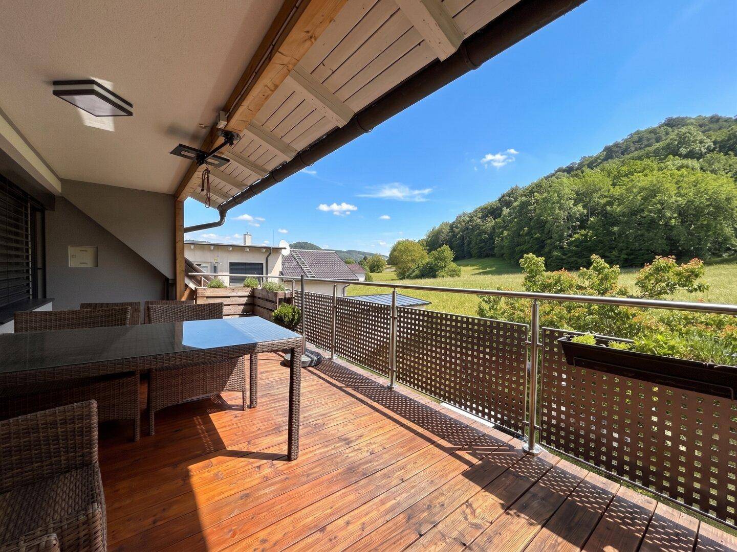 Heller Balkon mit bequemen Outdoor-Möbeln und einem schönen Ausblick auf die umliegende Natur.