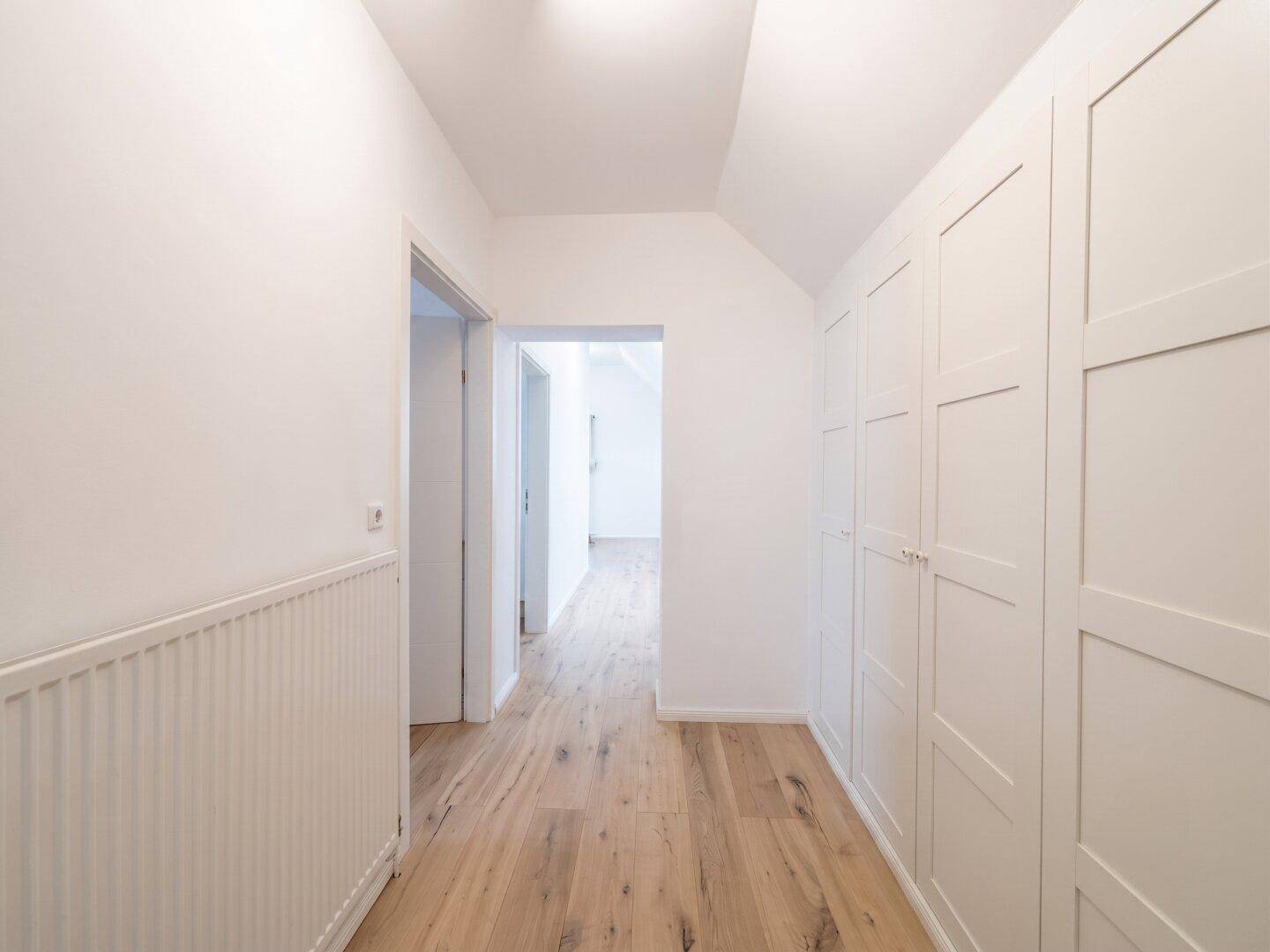 Geräumiger Flur mit praktischen Einbauschränken, Holzboden und hellen Wänden.