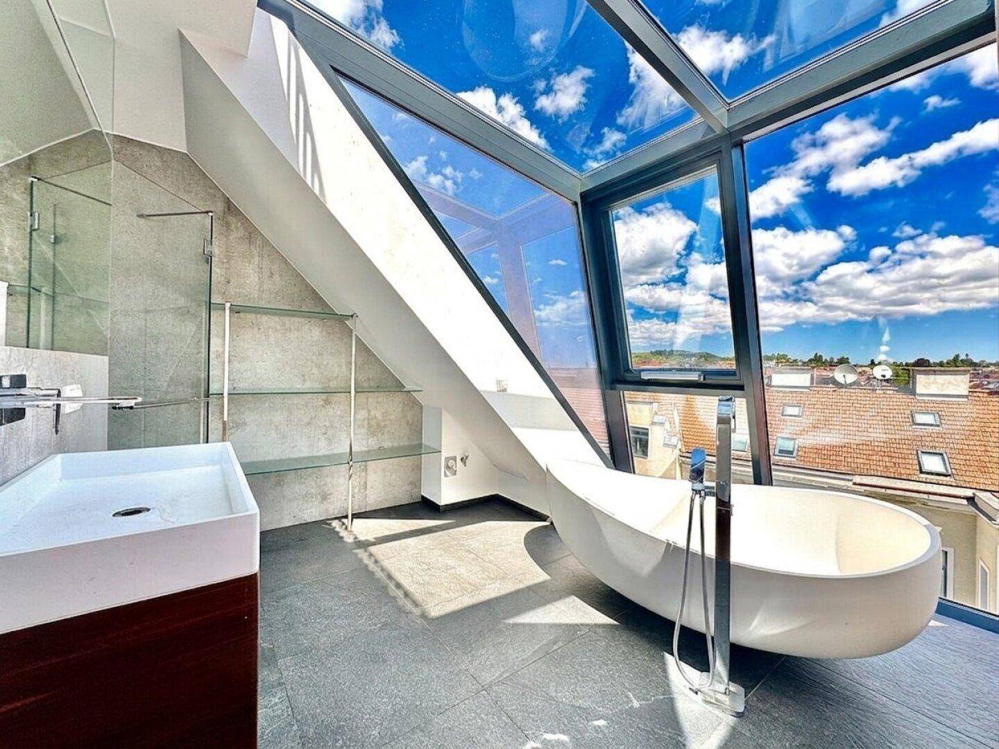 Modernes Badezimmer mit freistehender Badewanne, elegantem Waschbecken und großflächigen Glasfenstern.