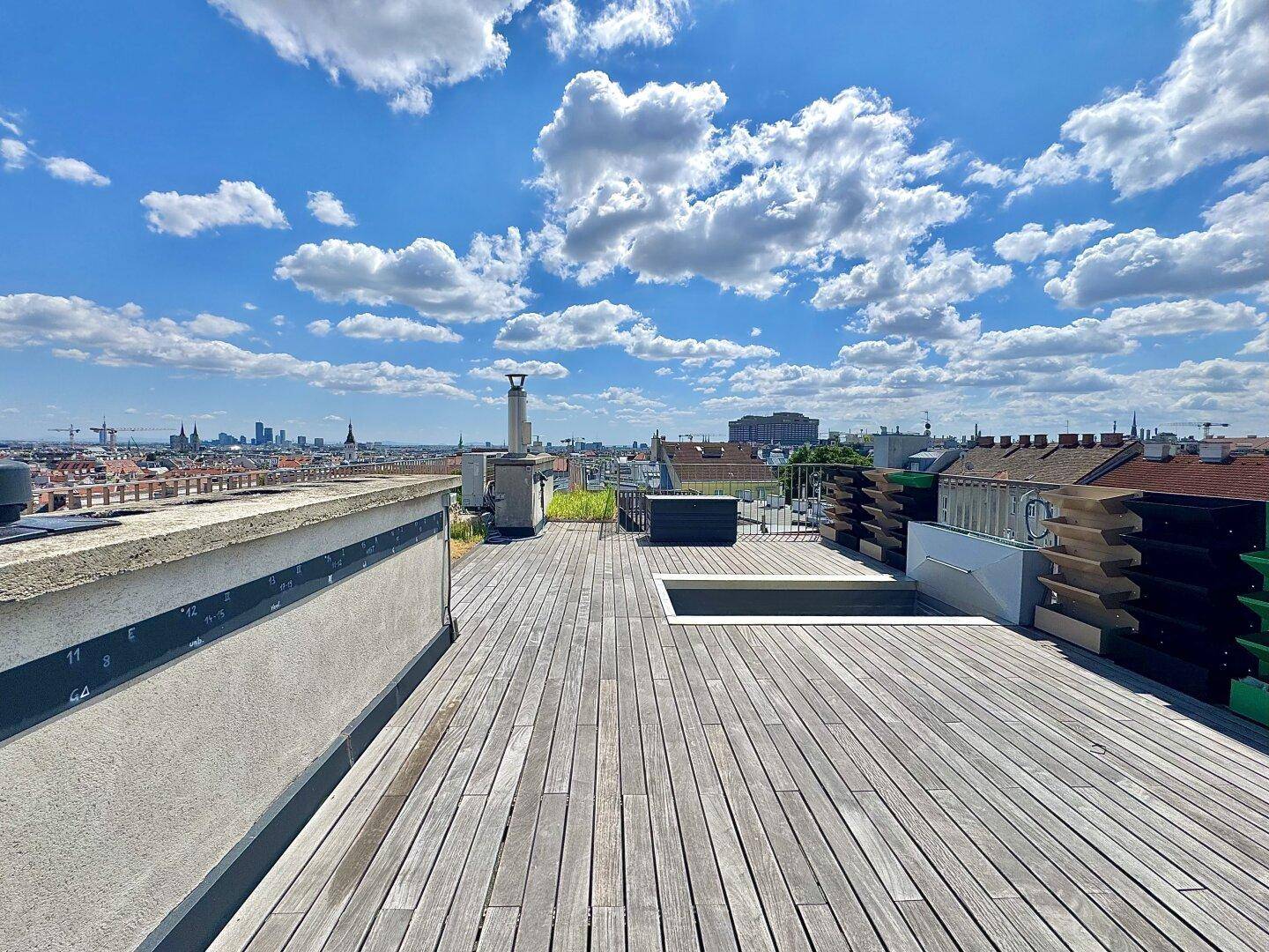 Weitläufige Dachterrasse mit Holzdeck und Panoramablick über die Stadt, perfekt für Outdoor-Aktivitäten.