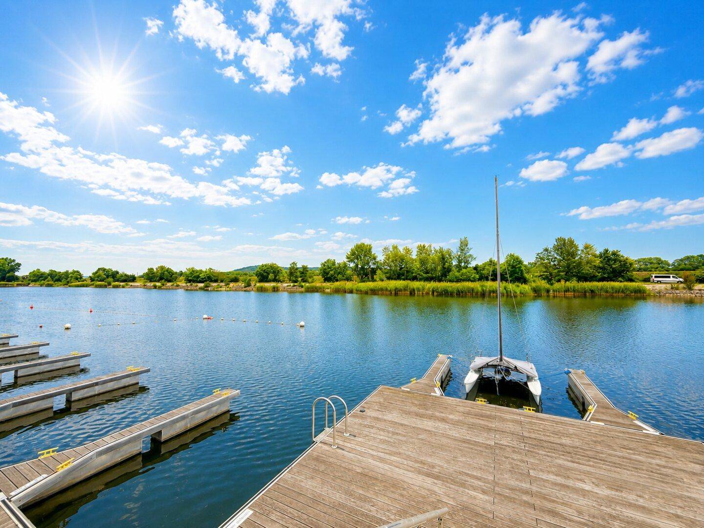 Bootsanlegestellen am See mit einem Segelboot und weitem Blick auf die Natur.