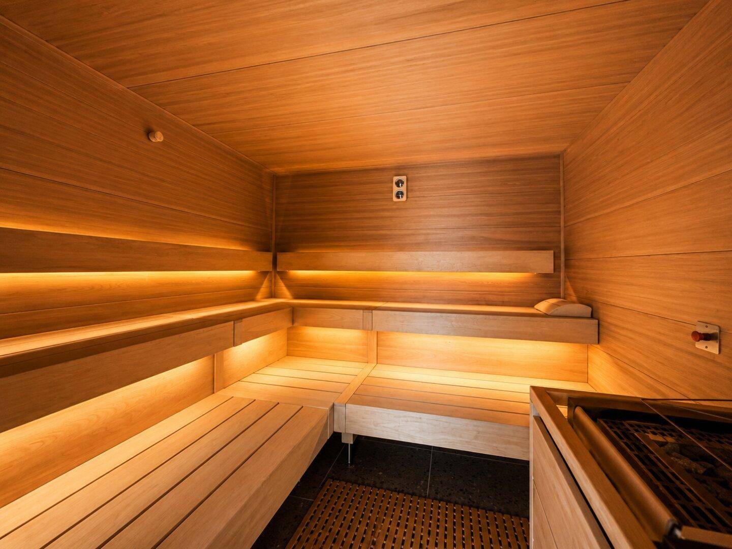 Geräumige Holzsauna mit mehreren Bänken und indirekter Beleuchtung für Entspannung.