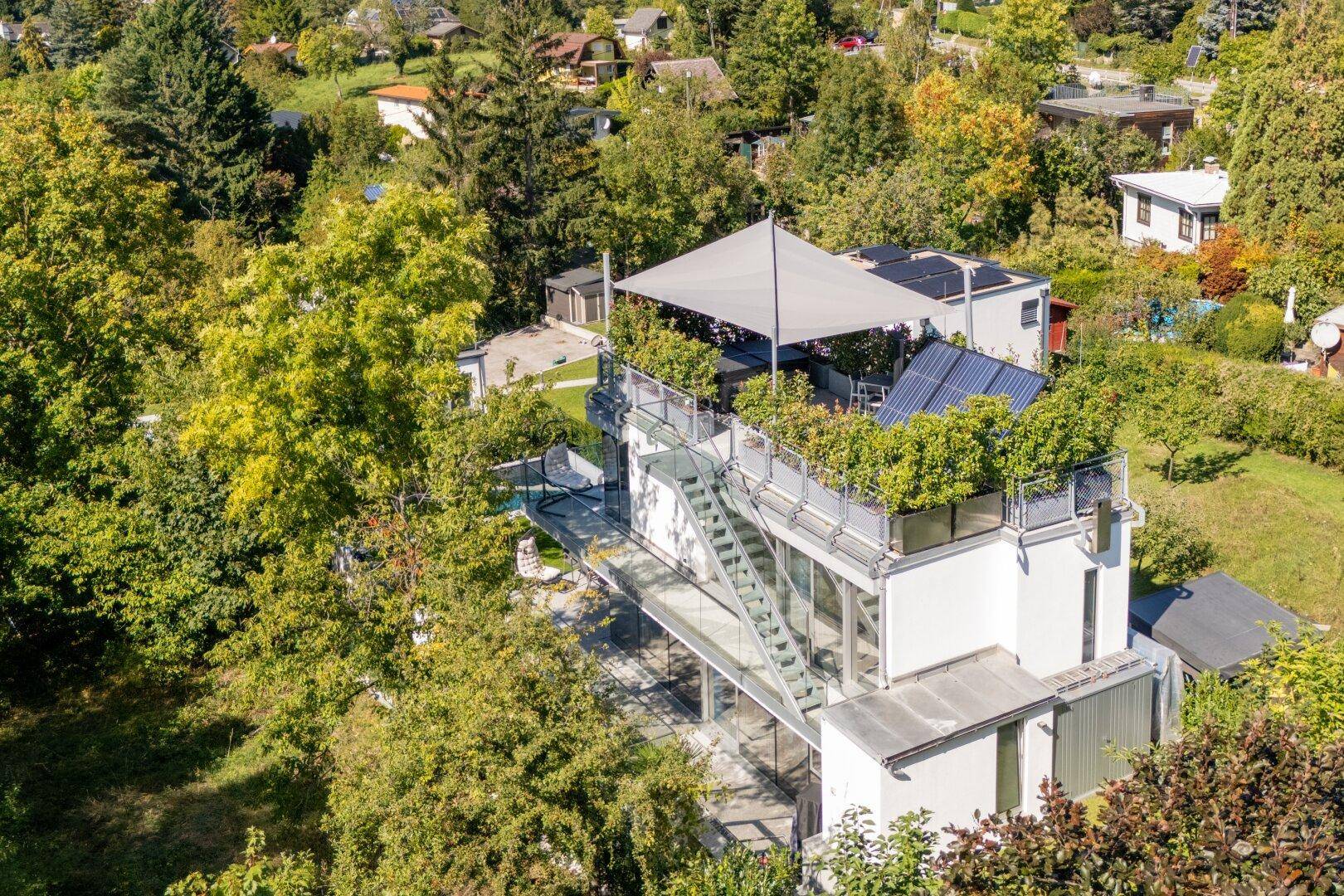Moderne Architektur mit Dachterrasse, Solarpaneelen und weitem Blick über die grüne Landschaft.