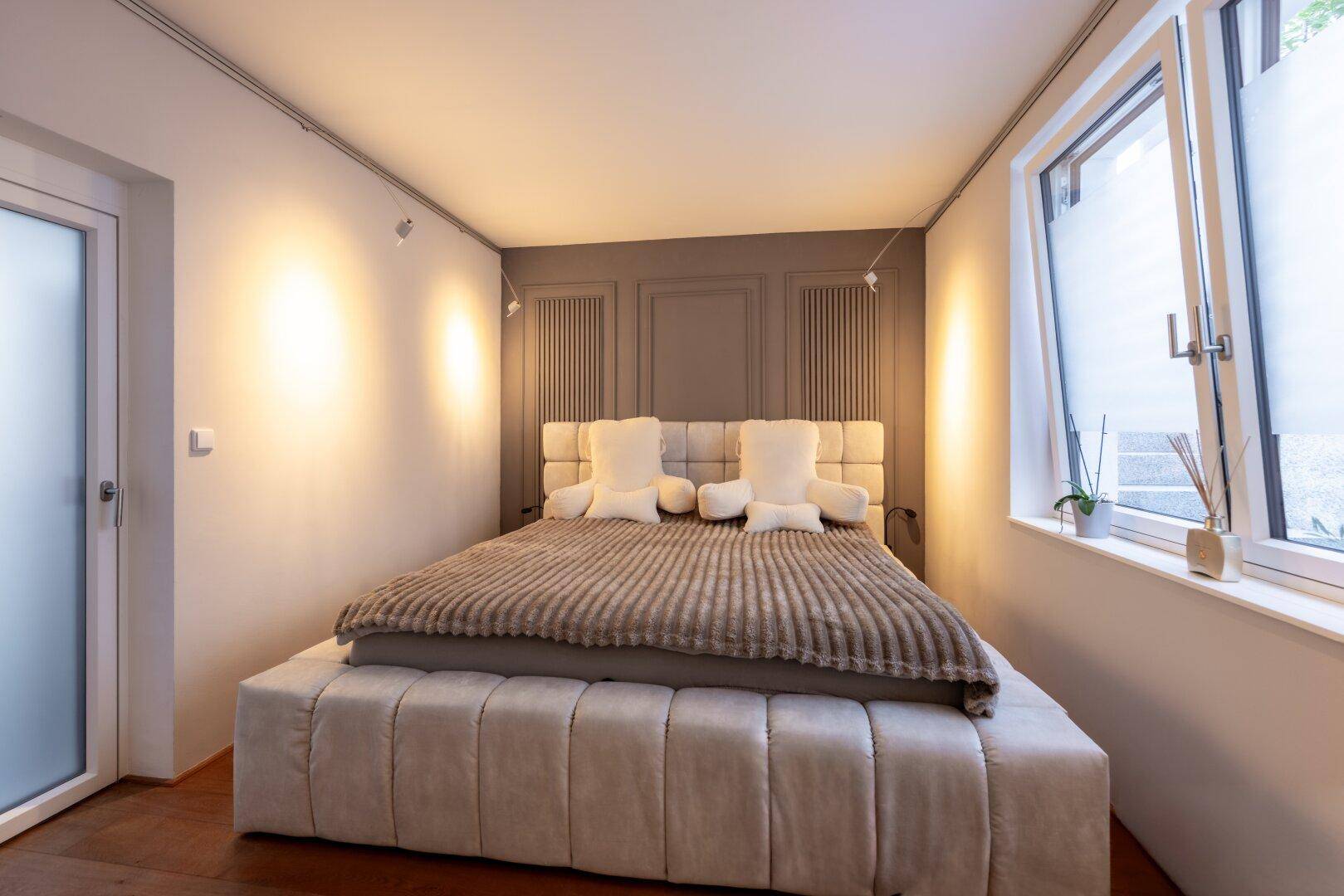 Gemütliches Schlafzimmer mit großem Bett, modernem Wanddesign und natürlichem Lichteinfall.