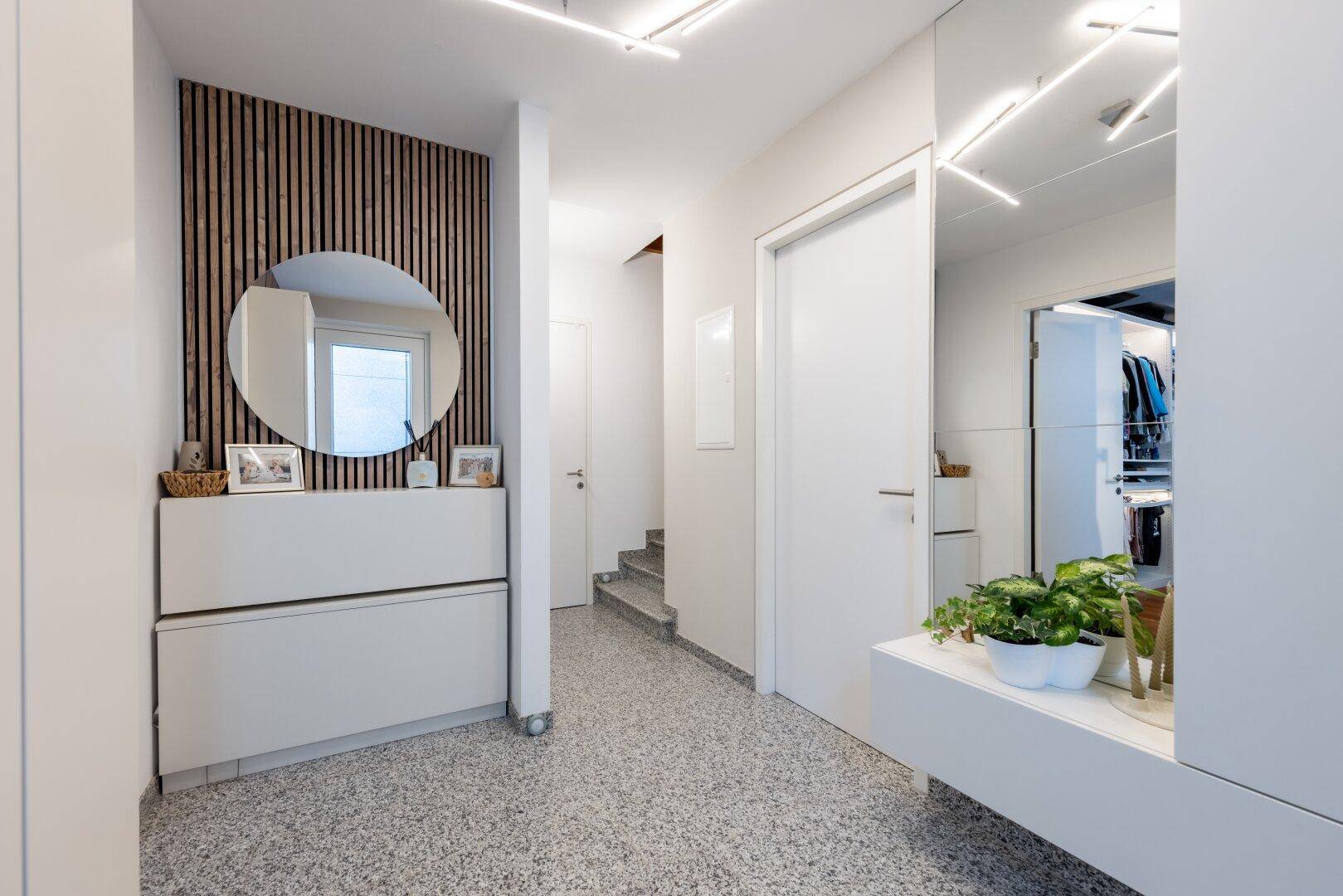 Heller Flur mit modernem Spiegel, Schuhschrank und stilvollem Terrazzoboden.