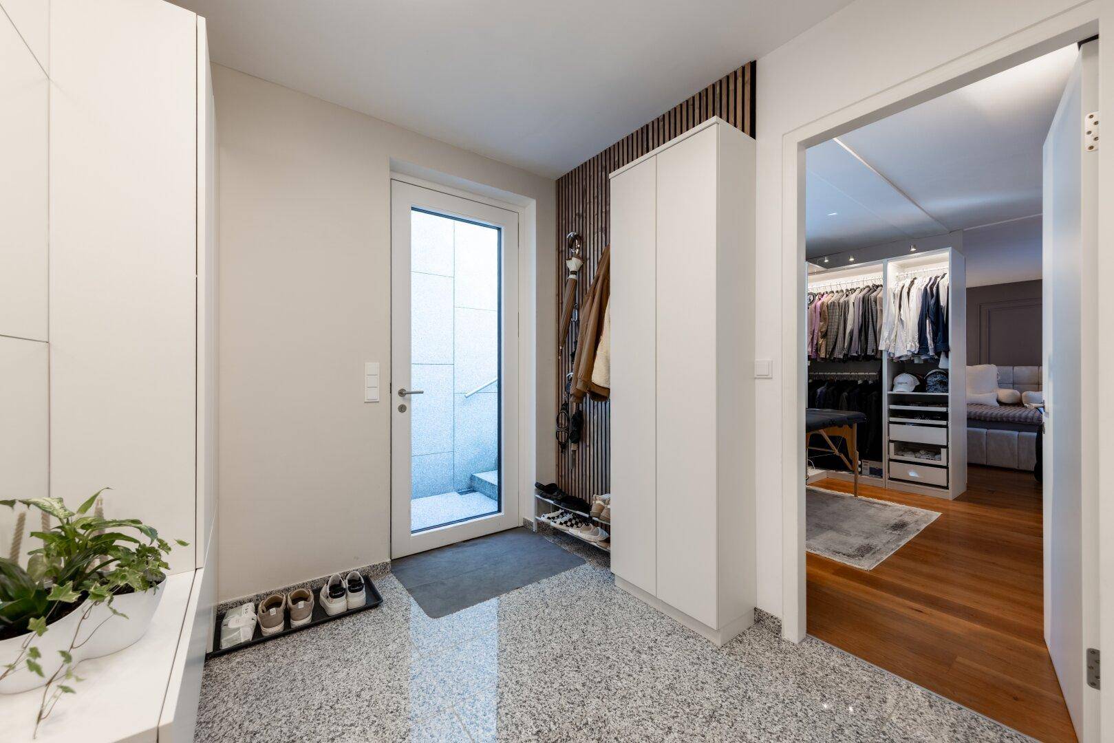 Eingangsbereich mit Terrazzoboden, Garderobe und Blick in einen begehbaren Kleiderschrank.