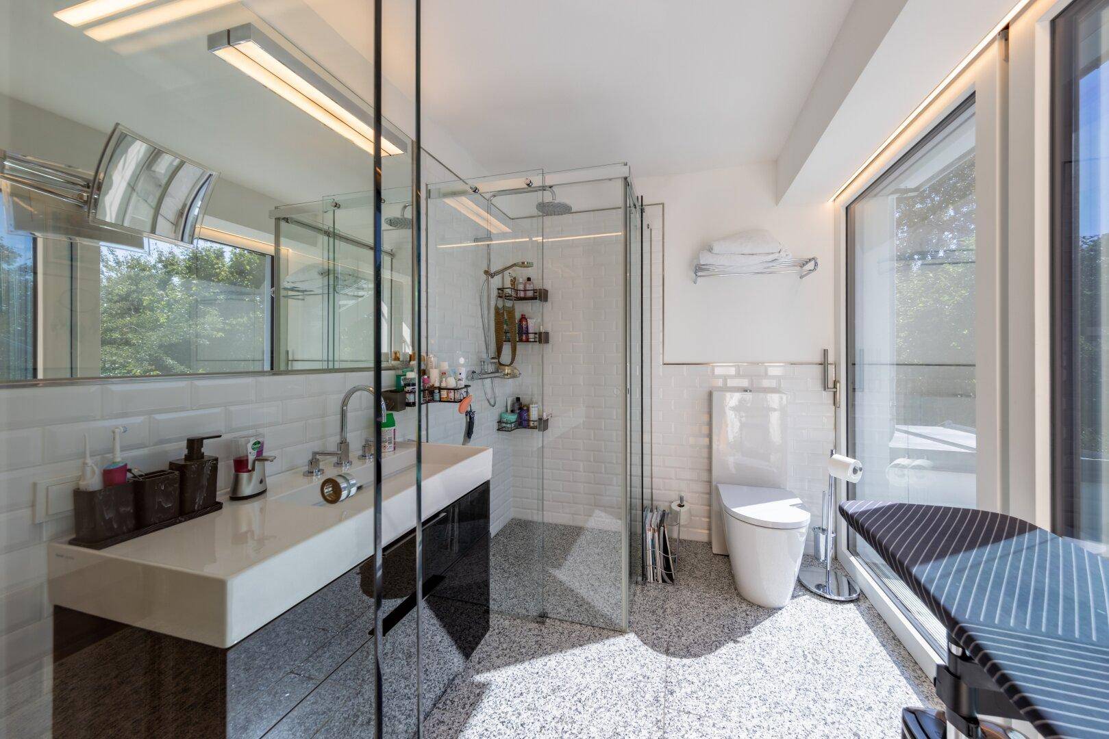 Modernes Badezimmer mit begehbarer Dusche, Doppelwaschbecken und großen Fenstern für viel Licht.