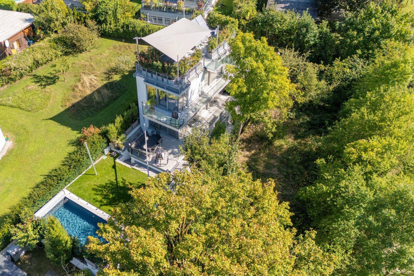 Luftaufnahme des modernen Hauses mit Pool und üppiger grüner Umgebung.