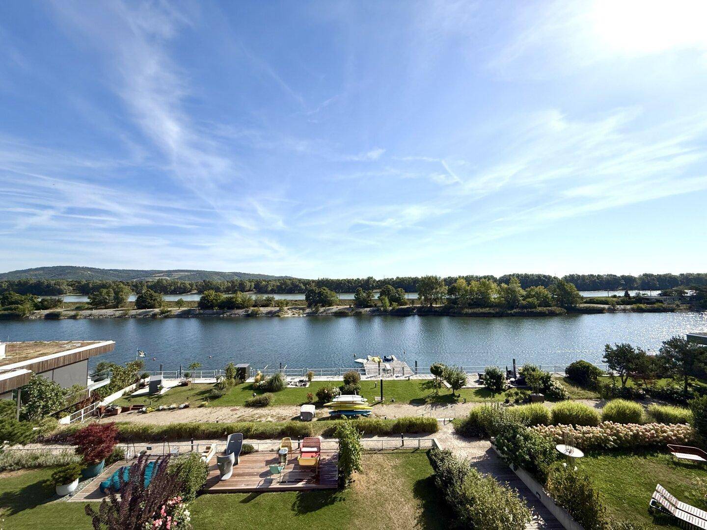 Weitläufiger Blick über den See mit grünen Ufern und einem privaten Steg.