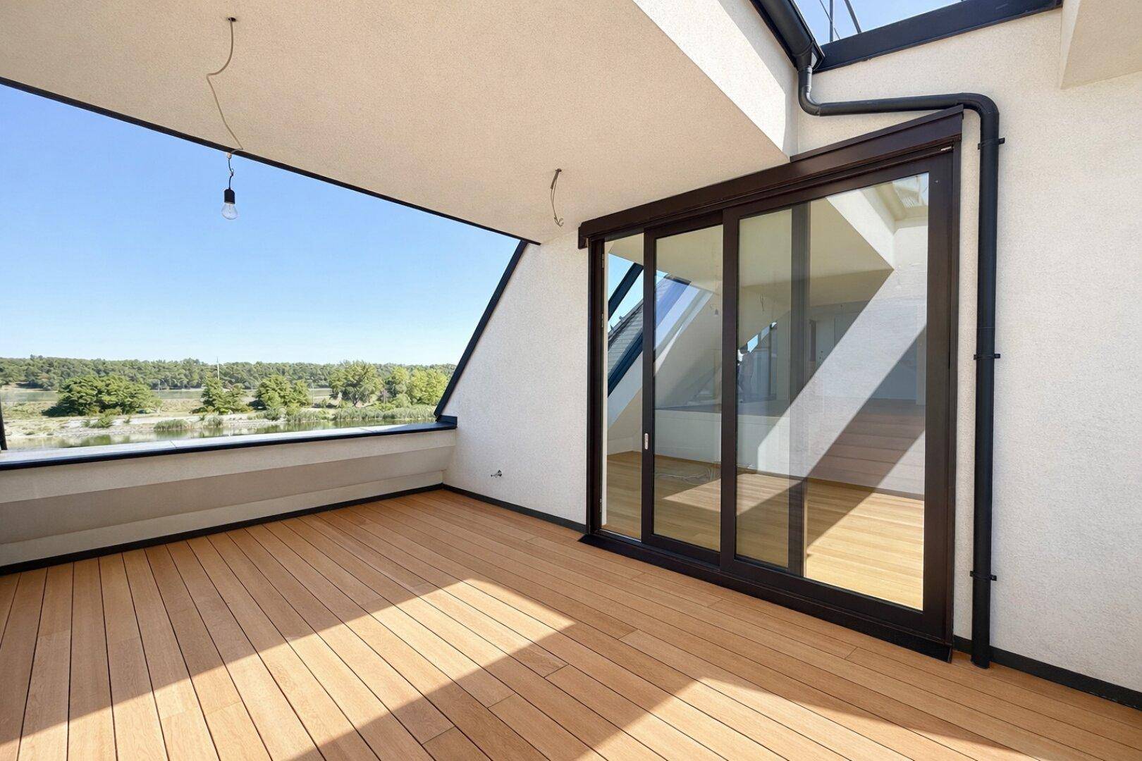 Überdachter Balkon mit Holzboden und weitem Blick auf den See und die umliegende Natur.