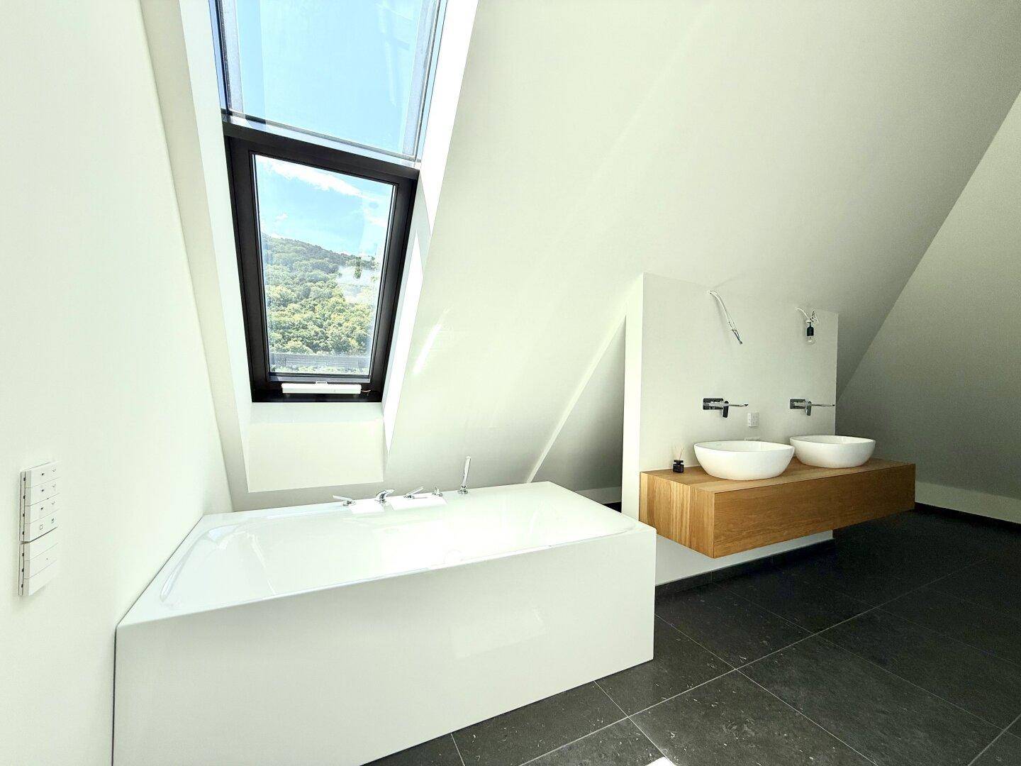 Elegantes Badezimmer mit freistehender Badewanne, Doppelwaschbecken und Dachfenster.