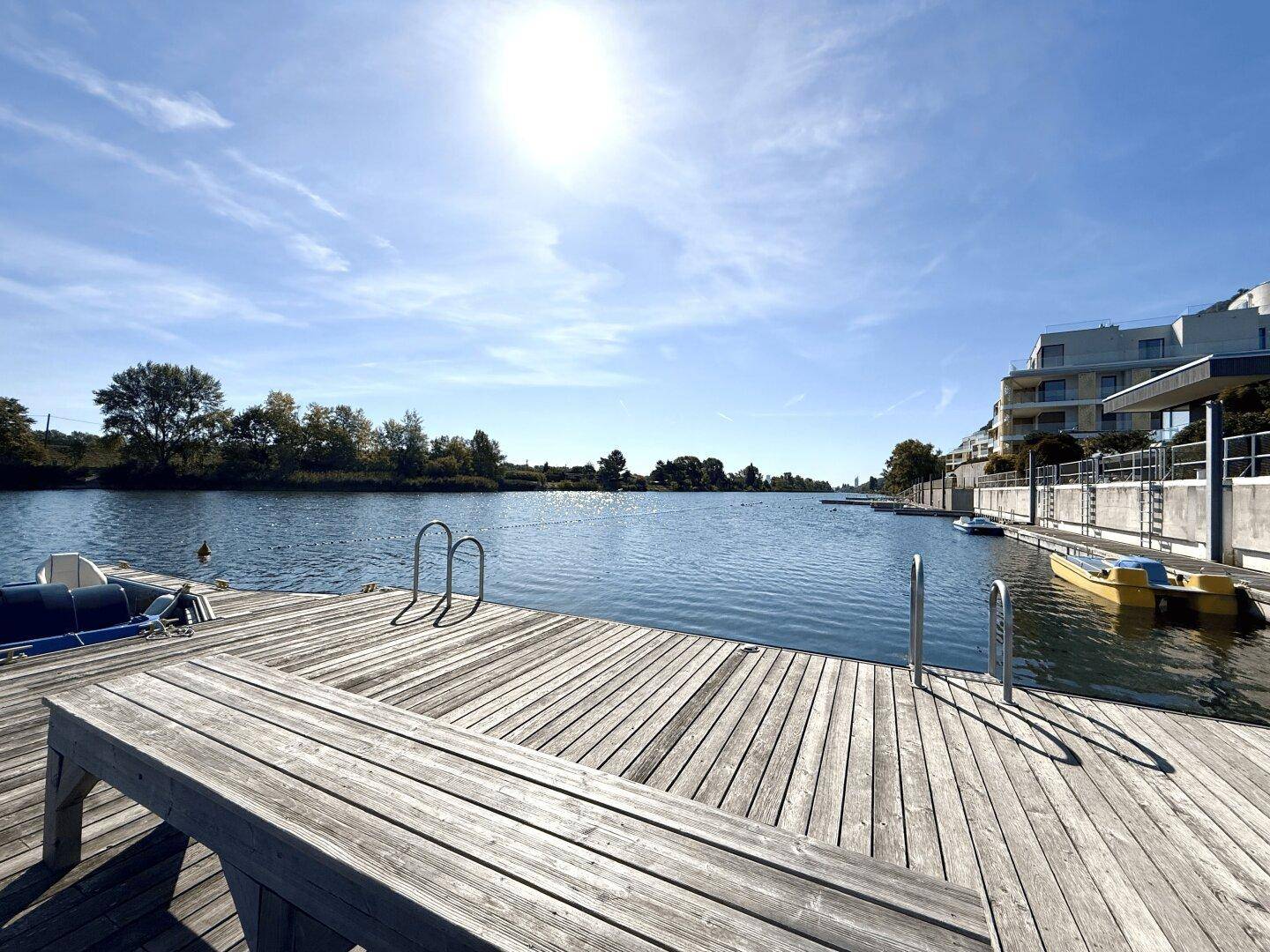 Große Holzterrasse am Wasser mit Sitzbank und direktem Zugang zum See.