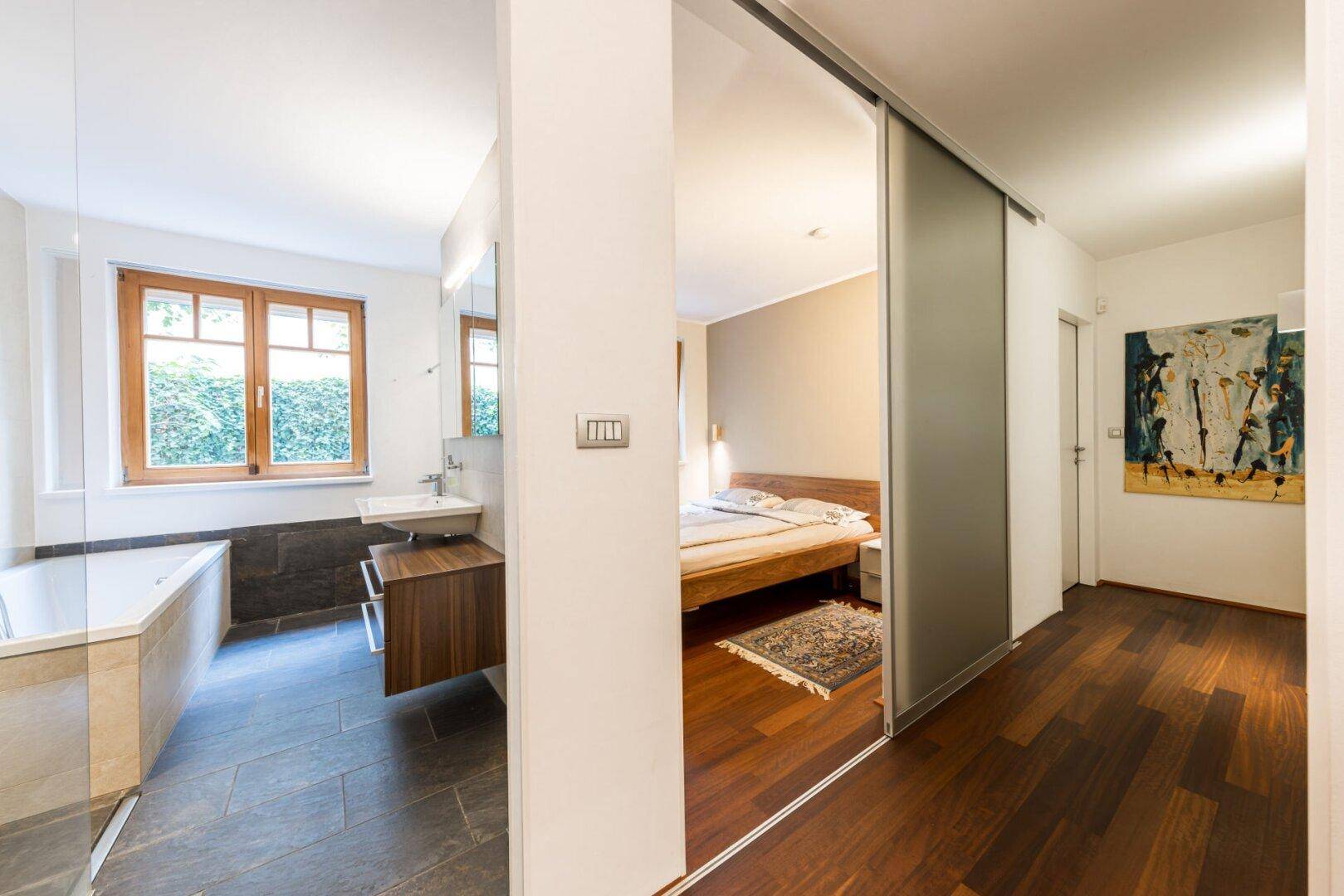 Heller Flur mit Holzboden, der zu einem Schlafzimmer und einem modernen Badezimmer führt.