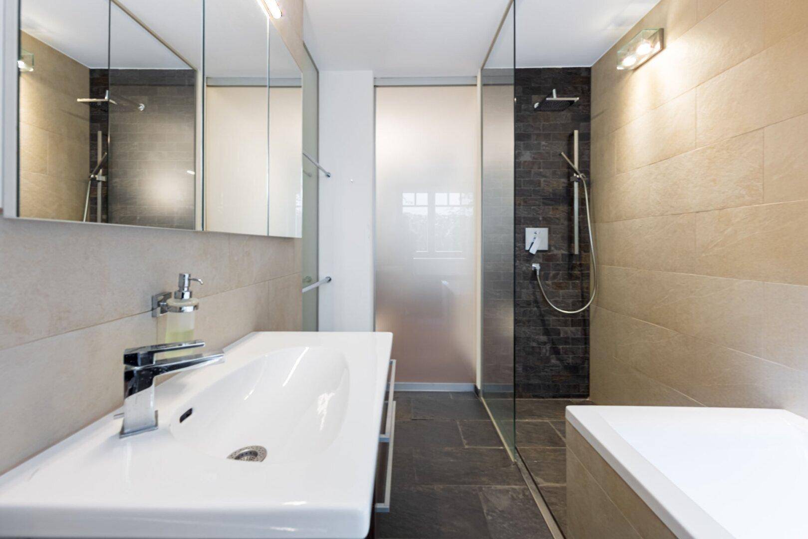 Helles Badezimmer mit großer Duschkabine, Einzelwaschbecken und Spiegelschrank.