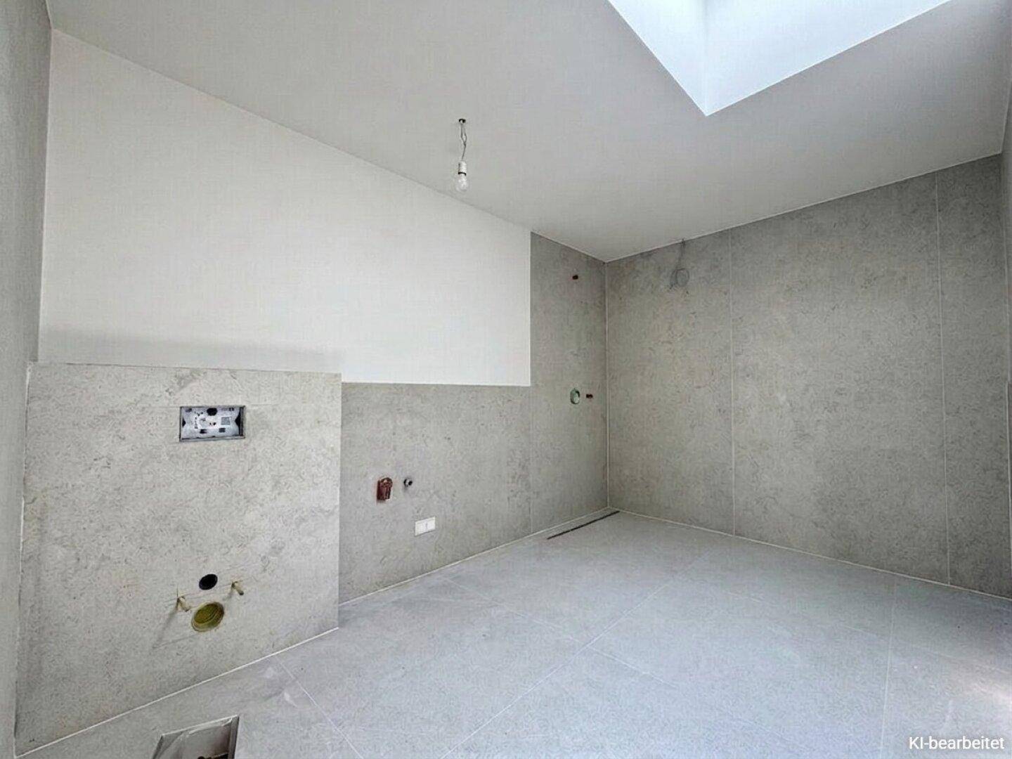 Unfertiges Badezimmer mit grauen Fliesen und einem Oberlicht, bietet viel Potenzial für modernes Design.