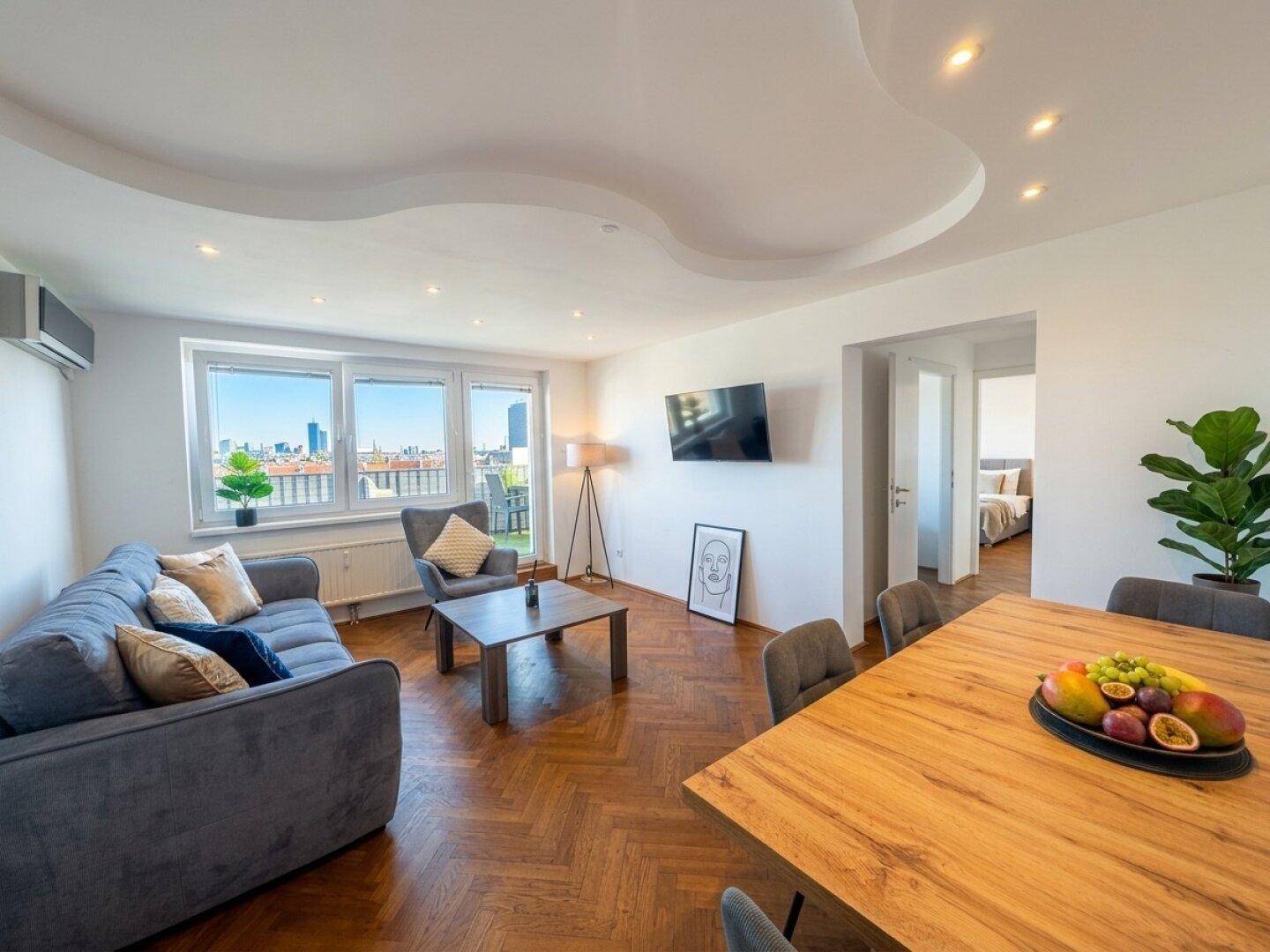 Modernes Wohn-Esszimmer mit Fischgrätparkett, indirekter Beleuchtung und Stadtblick.