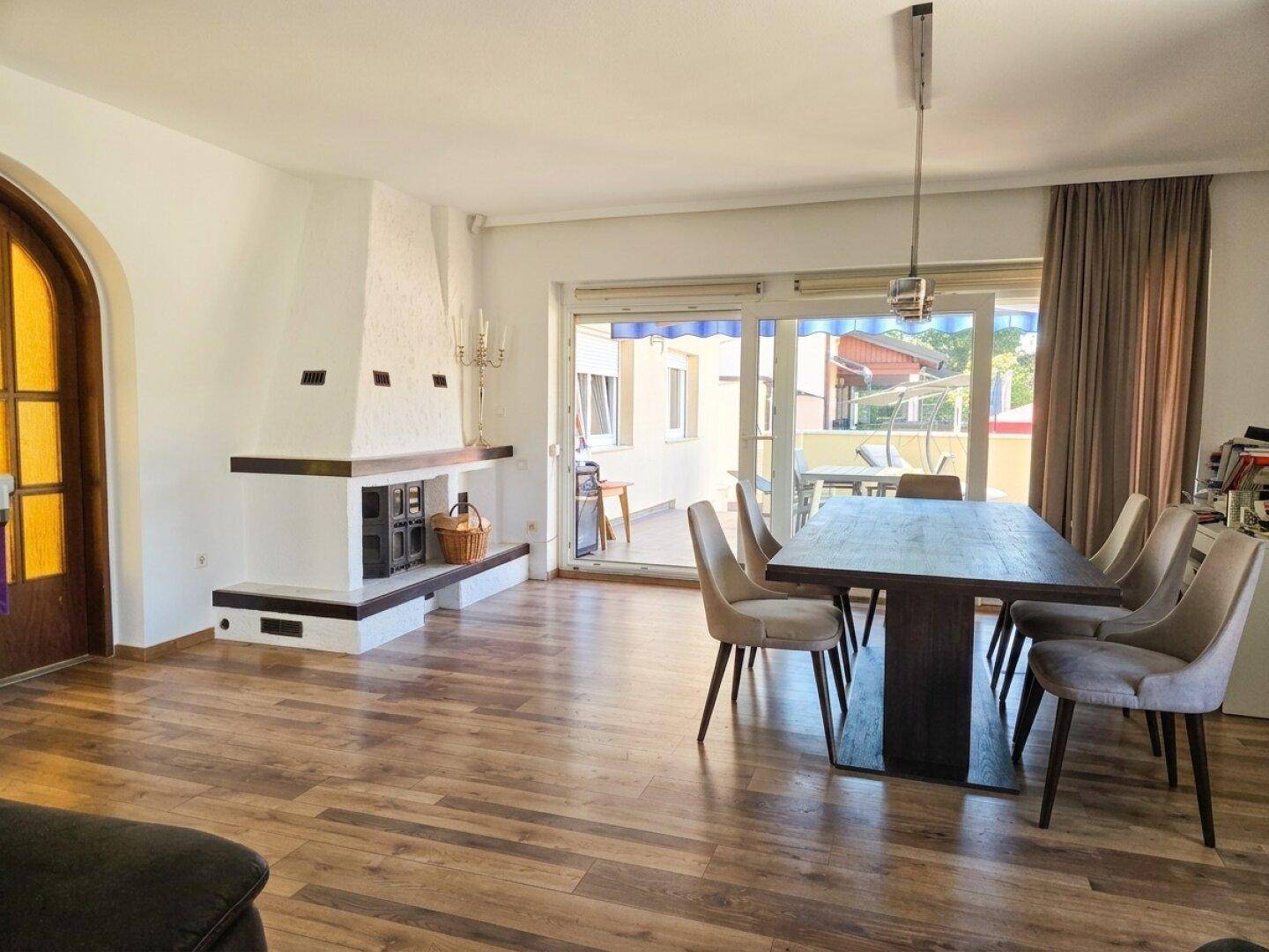 Geräumiger Wohn-Essbereich mit Kamin, Holzboden und Zugang zur Terrasse.