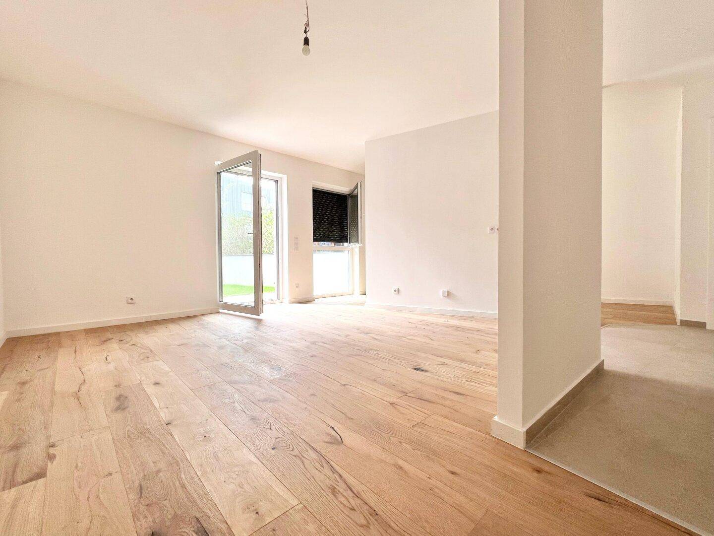 Lichtdurchfluteter Wohnbereich mit Holzboden und Zugang zu einem Außenbereich.