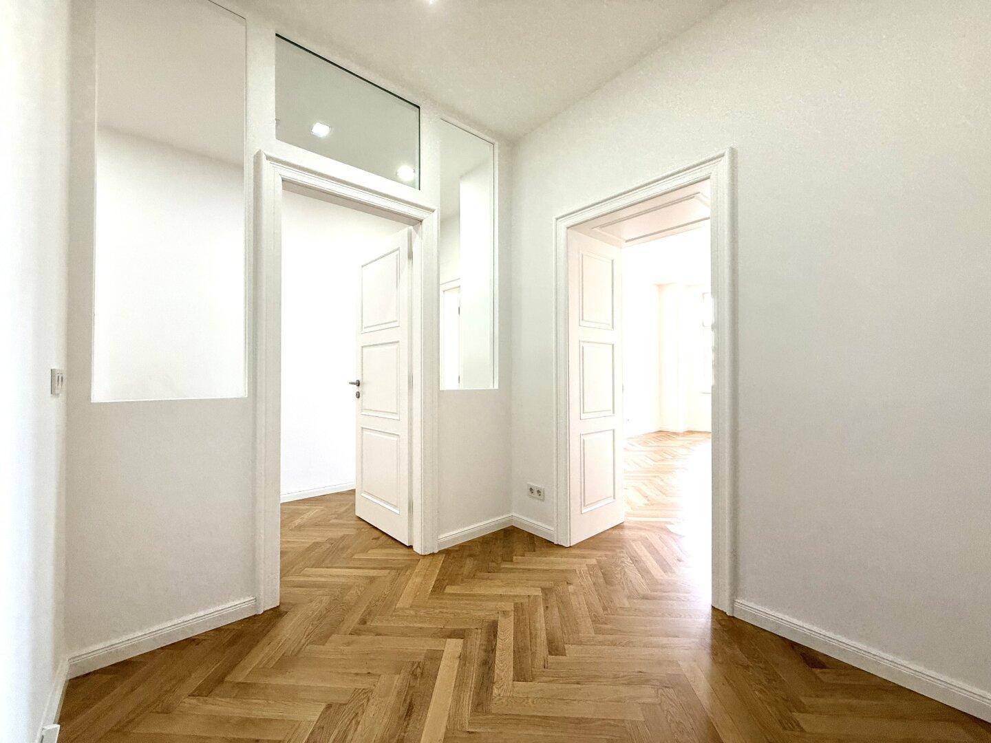Eleganter Flur mit Fischgrätparkett und hohen Türen, die den Zugang zu den verschiedenen Wohnbereichen ermöglichen.