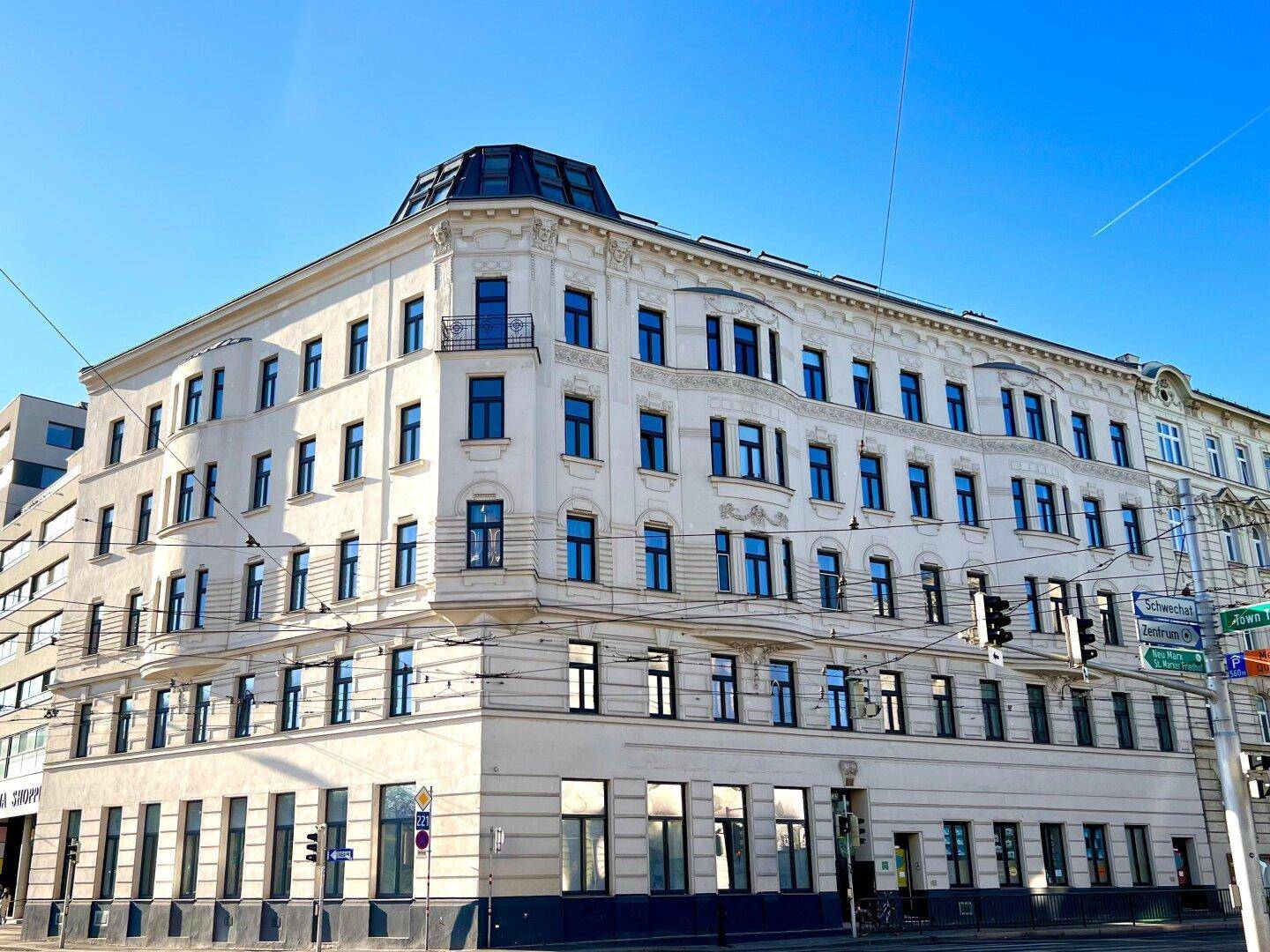 Elegantes Eckgebäude mit klassischer Architektur und vielen Fenstern in einer städtischen Umgebung.