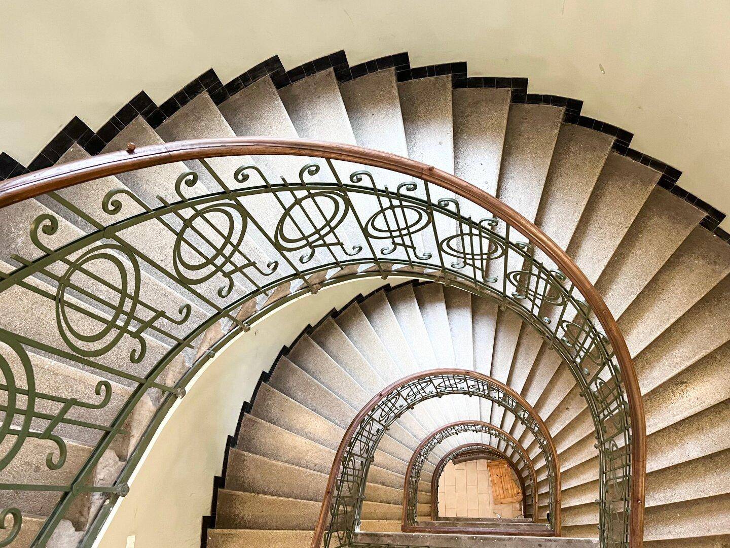 Beeindruckendes spiralförmiges Treppenhaus mit kunstvollem Geländer, das die Eleganz des Altbaus unterstreicht.