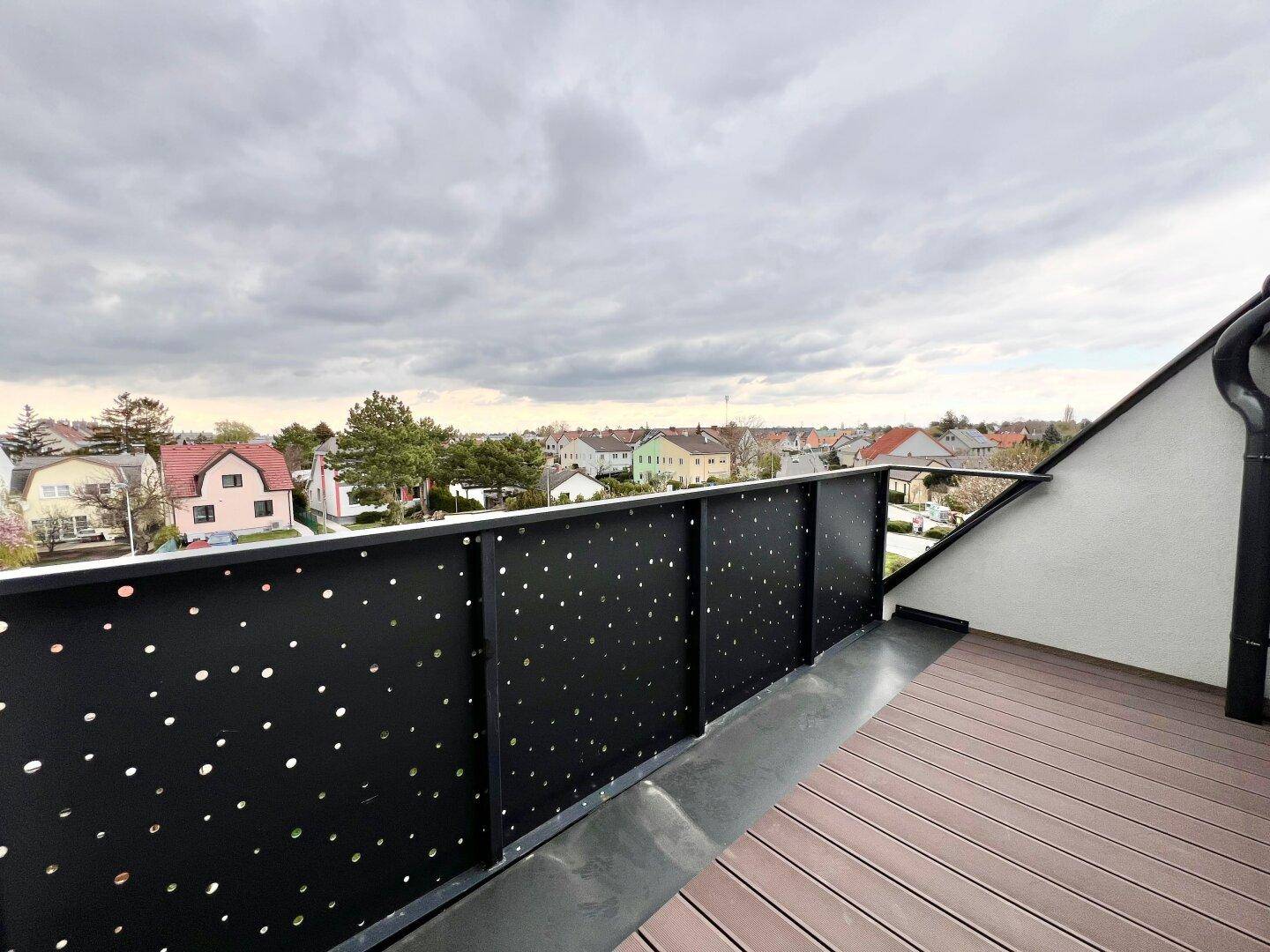 Balkon mit moderner Lochblech-Brüstung und weitem Blick über die Wohngegend.