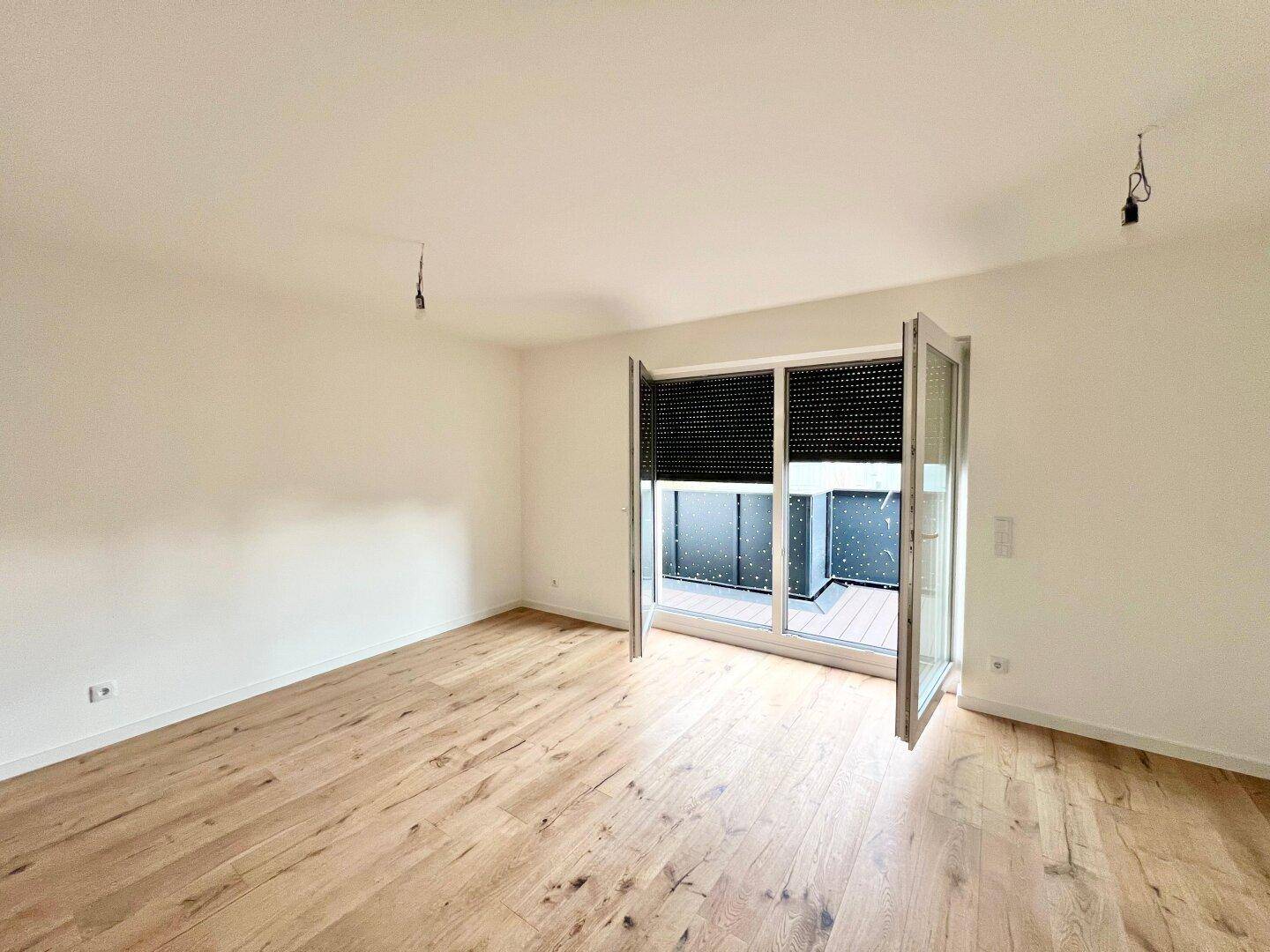 Geräumiges, helles Zimmer mit neuem Holzboden und großen Fenstern, bereit zur individuellen Gestaltung.