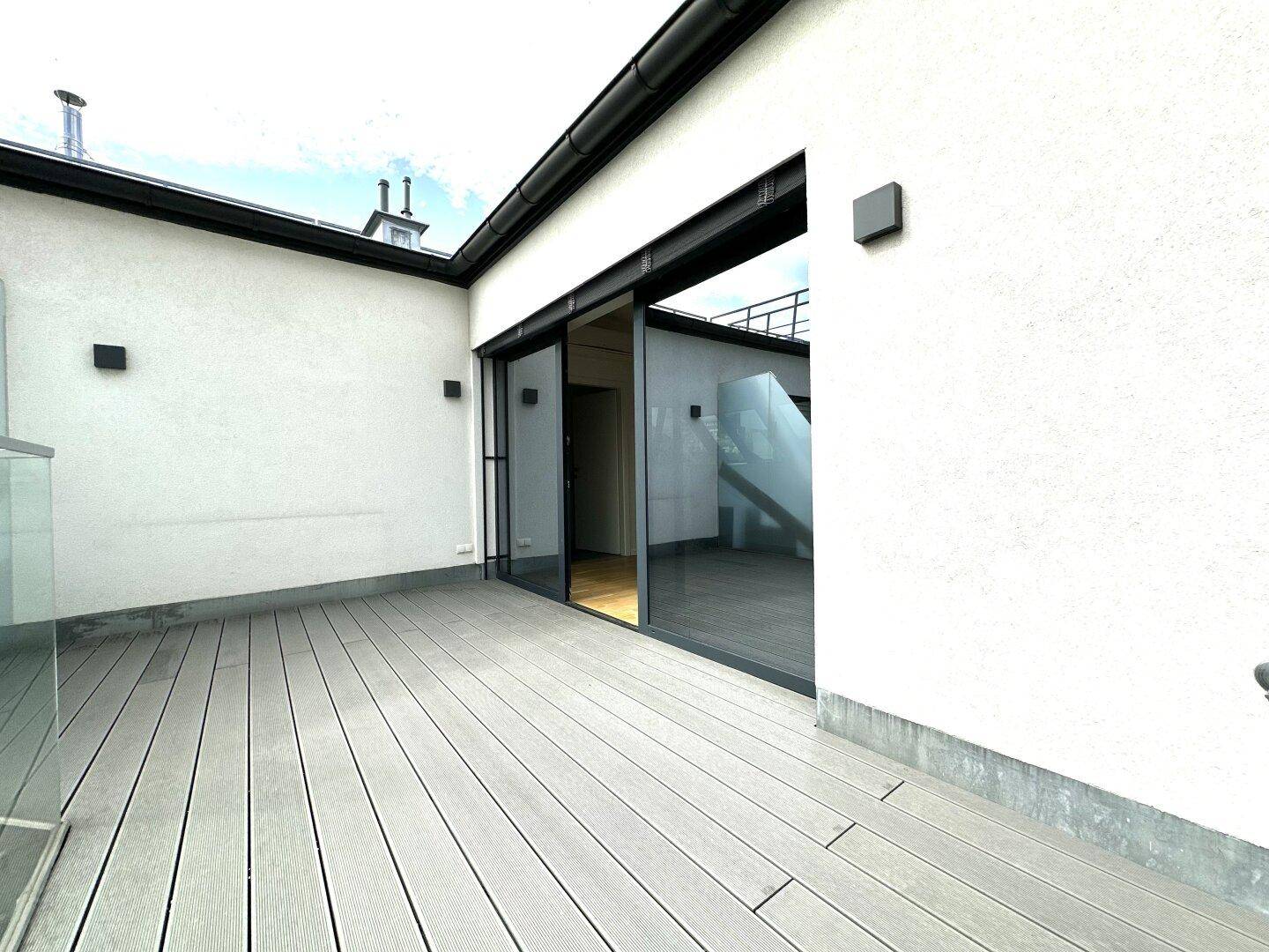 Geräumige Dachterrasse mit Holzdielenboden und Zugang zum Innenbereich.