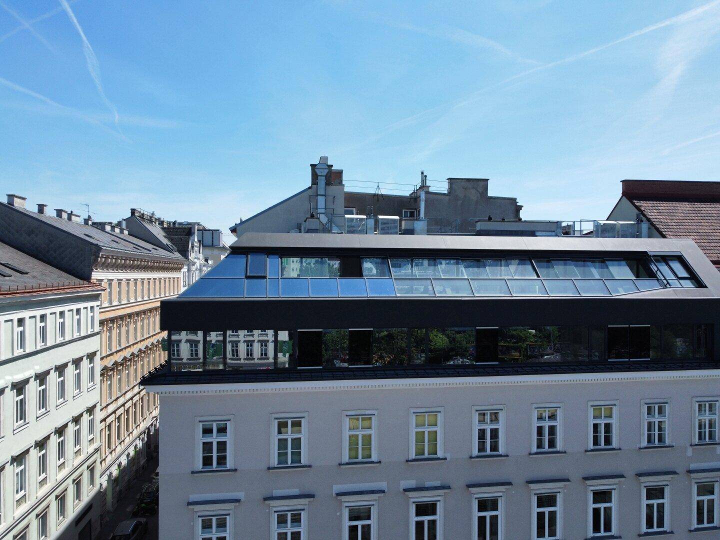 Moderne Dachkonstruktion mit großen Glasflächen auf einem historischen Gebäude.
