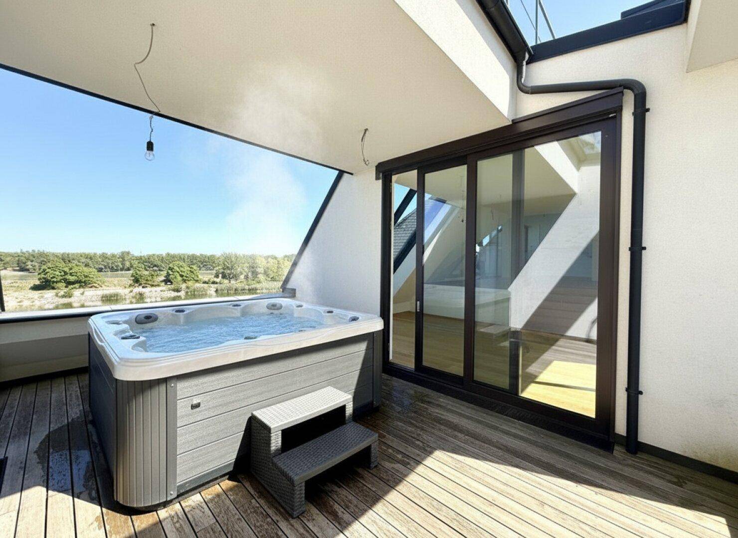 Moderne Dachterrasse mit Whirlpool und Holzboden, bietet einen weiten Blick auf die umliegende Natur.