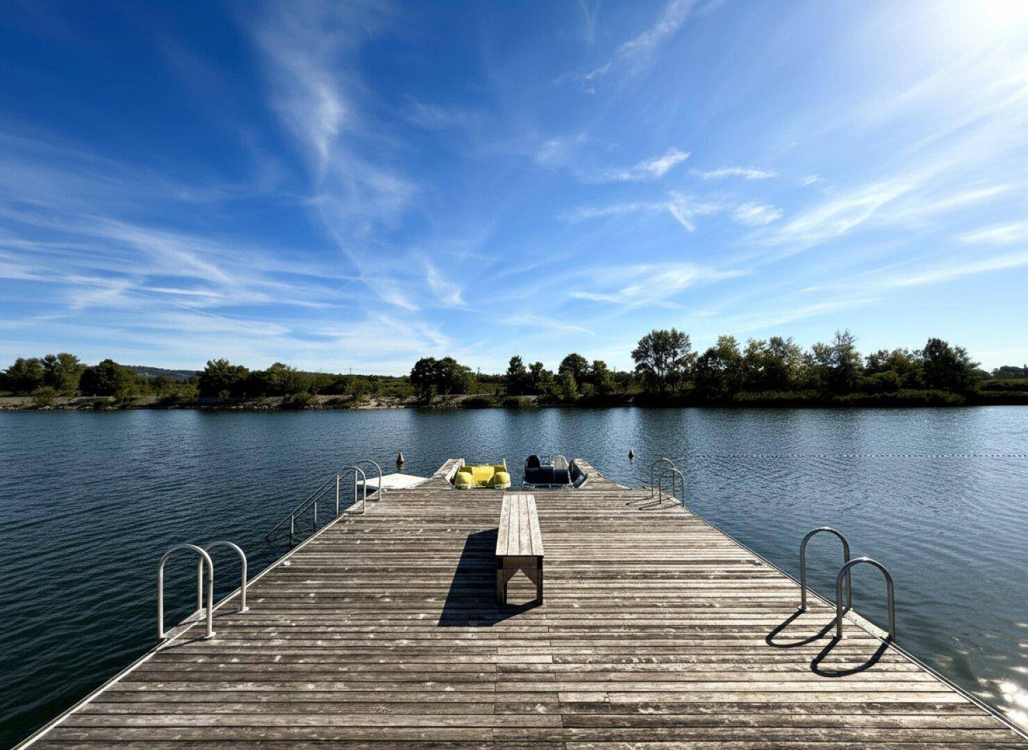Holzsteg führt in das ruhige Gewässer unter einem strahlend blauen Himmel.