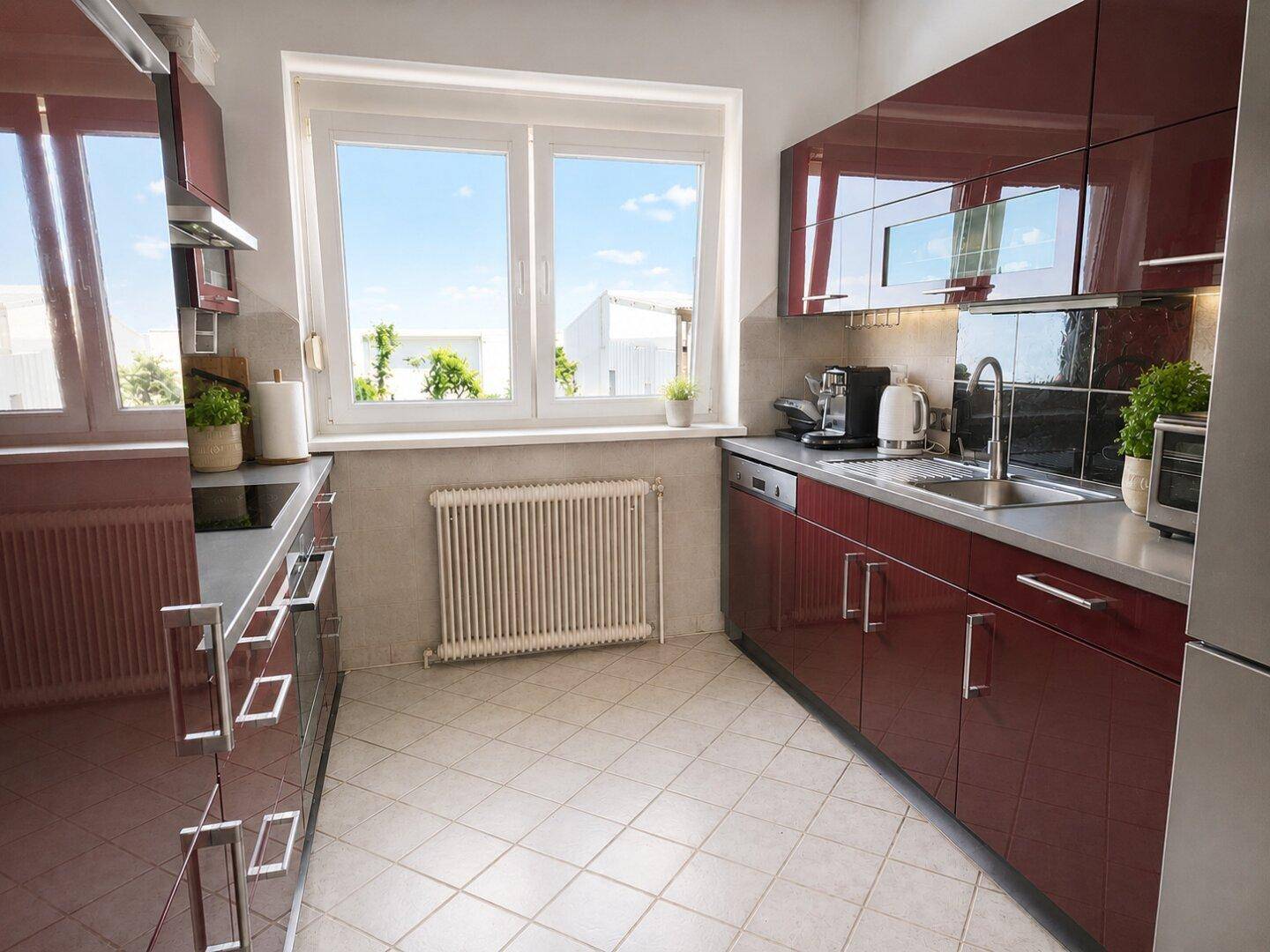 Moderne Küche mit weinroten Hochglanzschränken, Fenster und Fliesenboden.