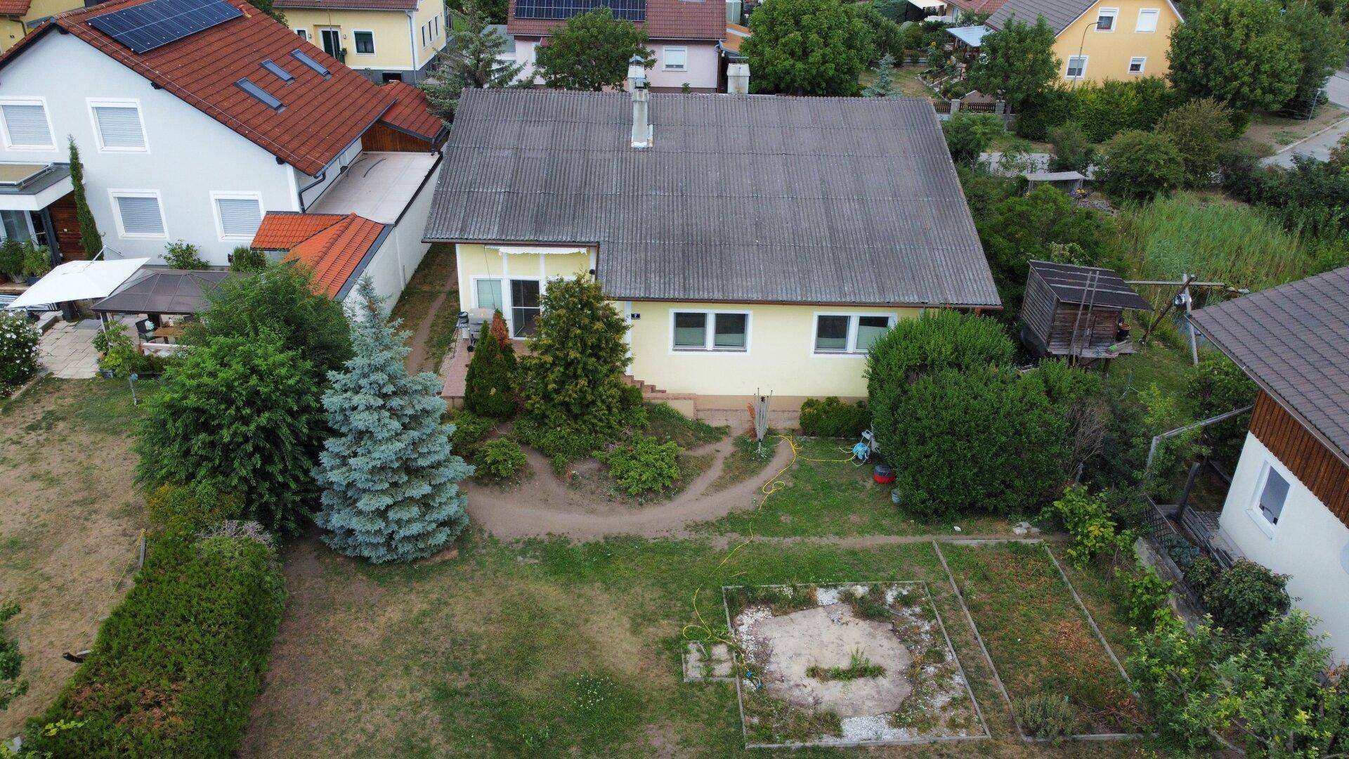 Hinterhof eines Einfamilienhauses mit Gartenbereich, Rasenfläche und umliegender Wohnbebauung.