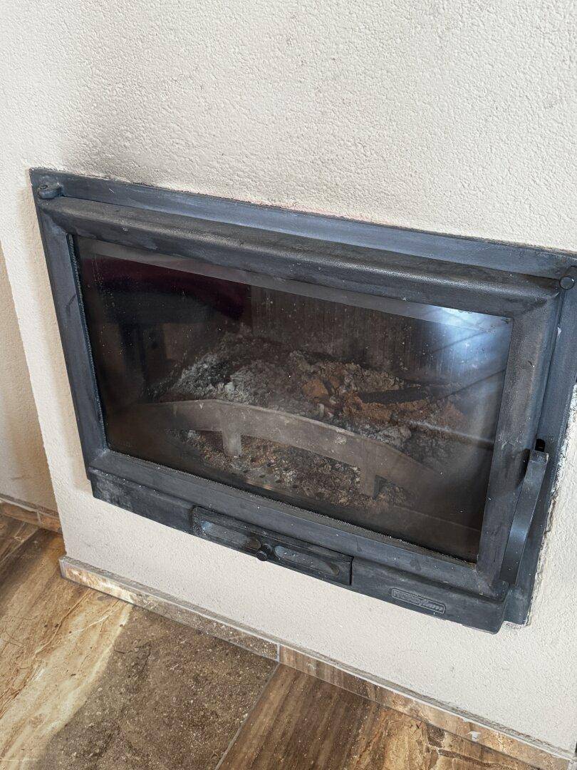 Nahaufnahme eines eingebauten Kamins mit Glasscheibe und Ascheresten.