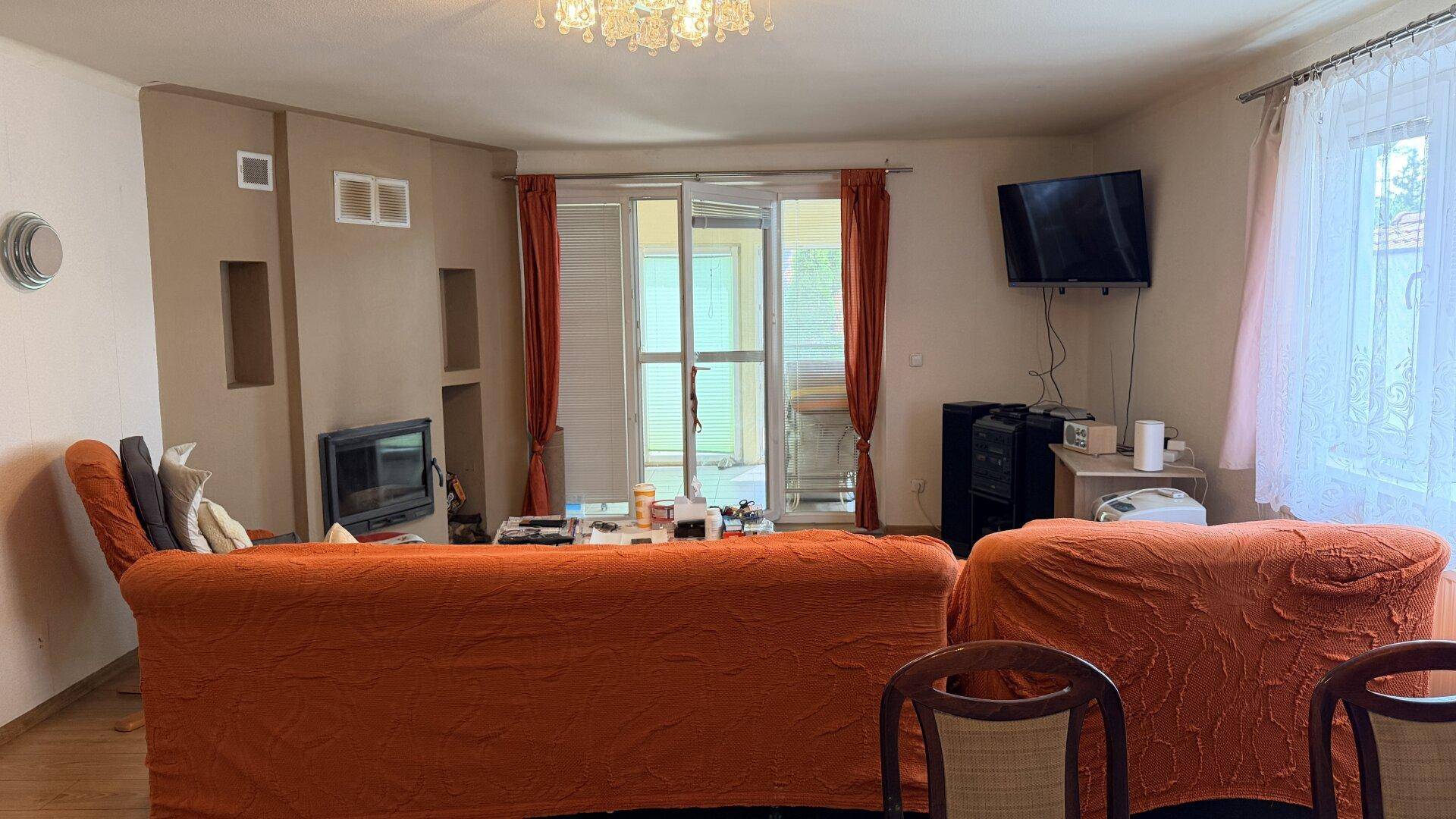 Wohnzimmer mit Kamin, Zugang zur Terrasse und Fernseher an der Wand.