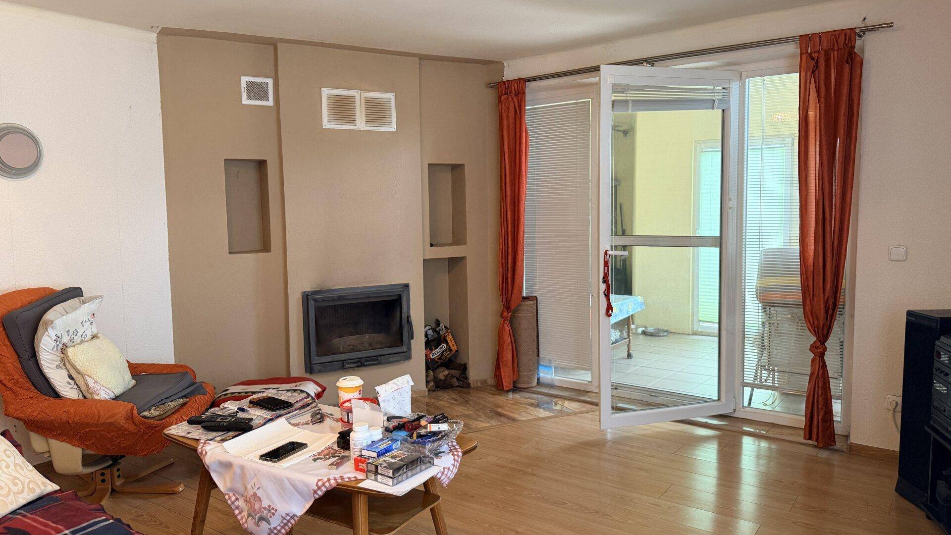 Wohnzimmer mit Kamin, Holzboden und Zugang zu einem Außenbereich.