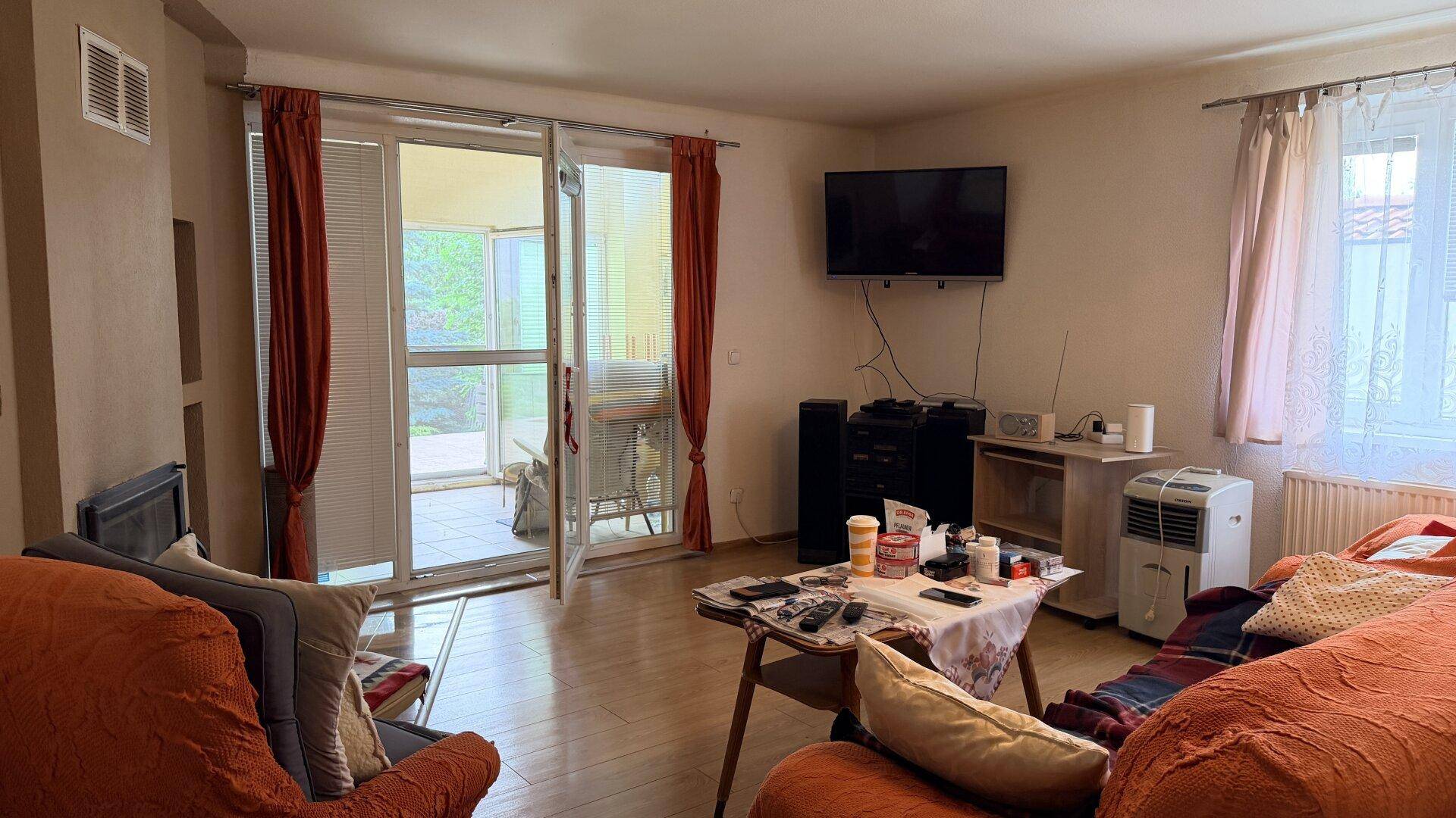Wohnzimmer mit Holzboden, Kamin und großen Fenstertüren zur Terrasse.
