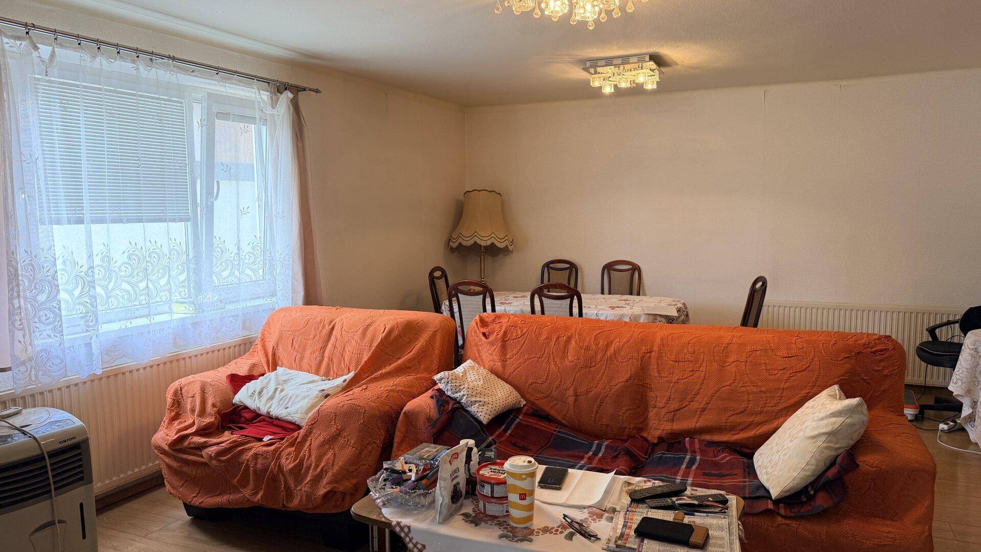 Heller Wohn- und Essbereich mit bequemen Sofas, Esstisch und großem Fenster.