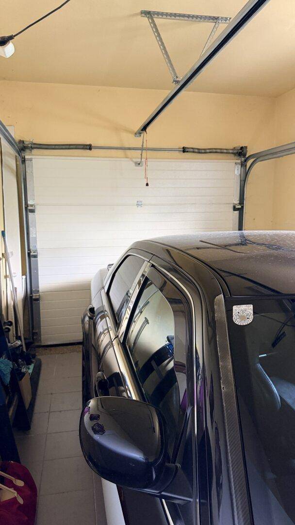 Garage mit einem geparkten Auto und einem Rolltor im Hintergrund.