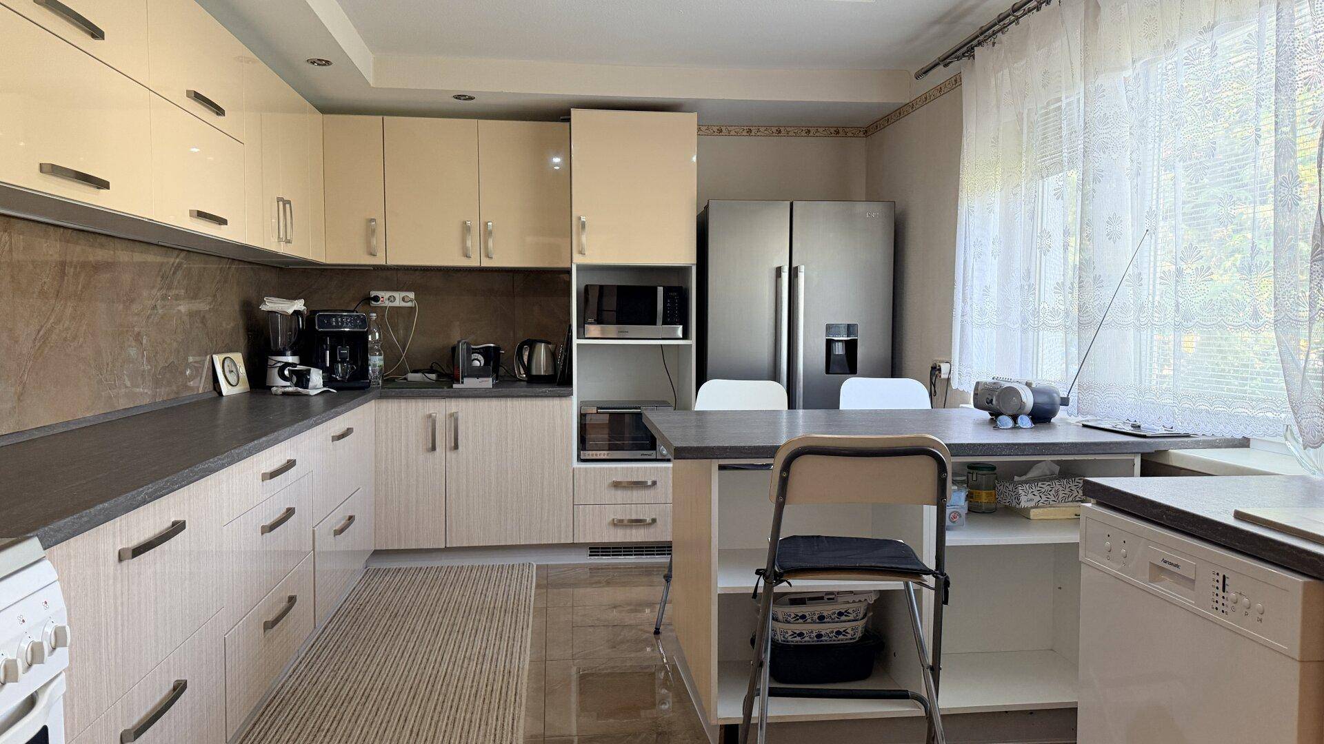 Geräumige Küche mit beigen Schränken, Essbereich und großem Kühlschrank mit Gefrierfach.