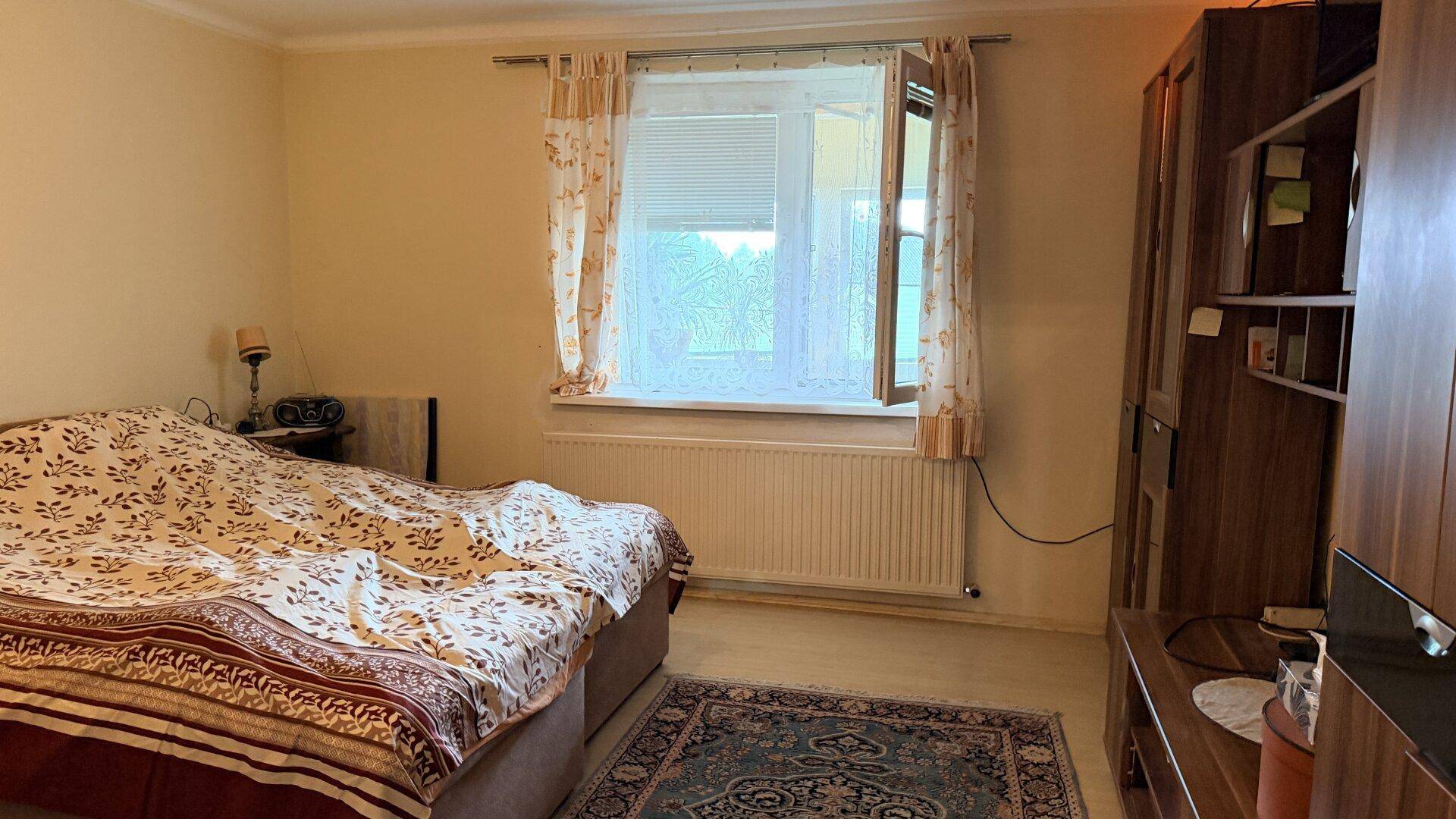 Gemütliches Schlafzimmer mit Doppelbett, Teppich und Fenster mit Blick ins Grüne.