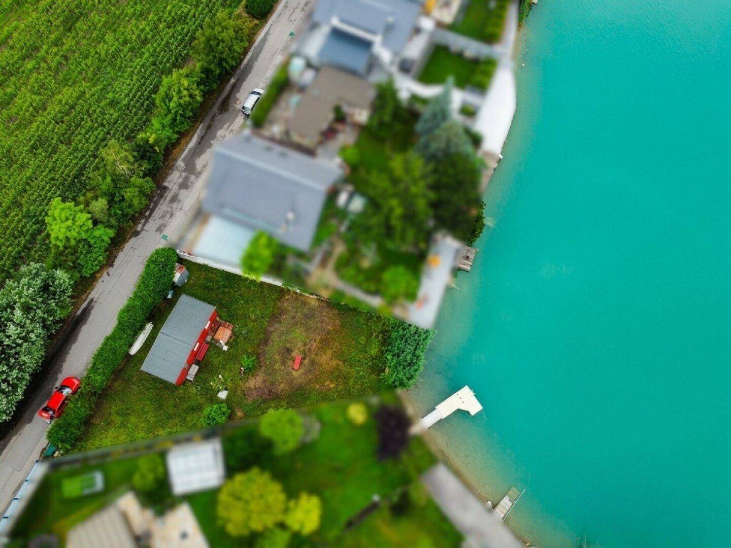 Übersichtliche Luftaufnahme eines Seegrundstücks mit Zufahrtsstraße und angrenzenden Grünflächen.