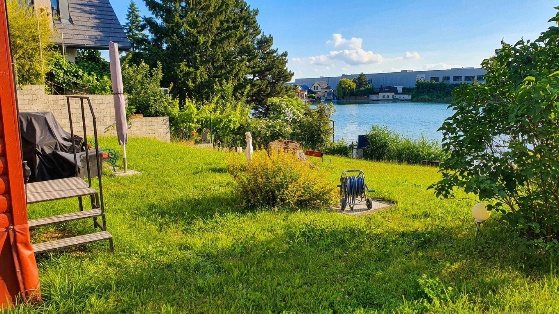 Gepflegter Garten mit Blick auf den See und Gartenutensilien, ideal zum Entspannen im Freien.