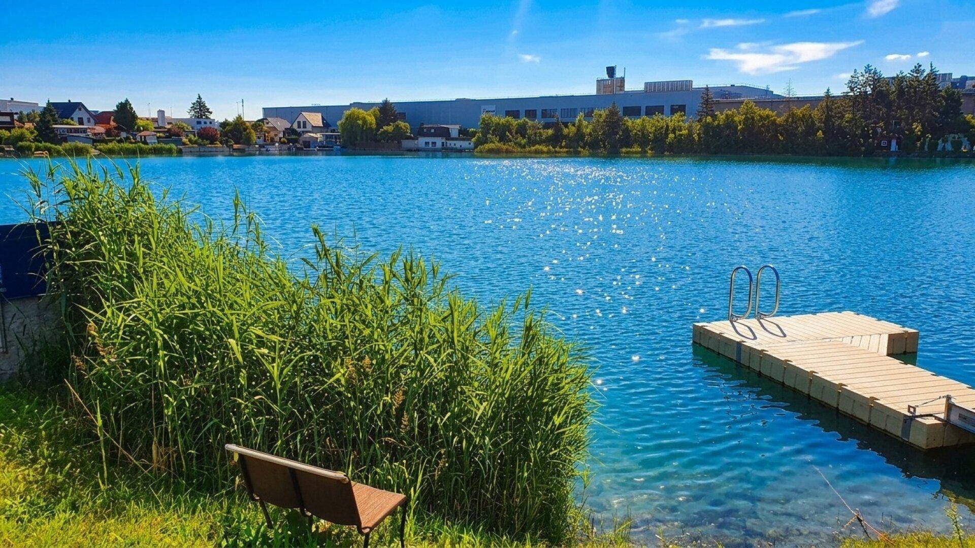 Klarer See mit schwimmendem Steg und Schilf am Ufer, perfekt für Wassersport und Erholung.