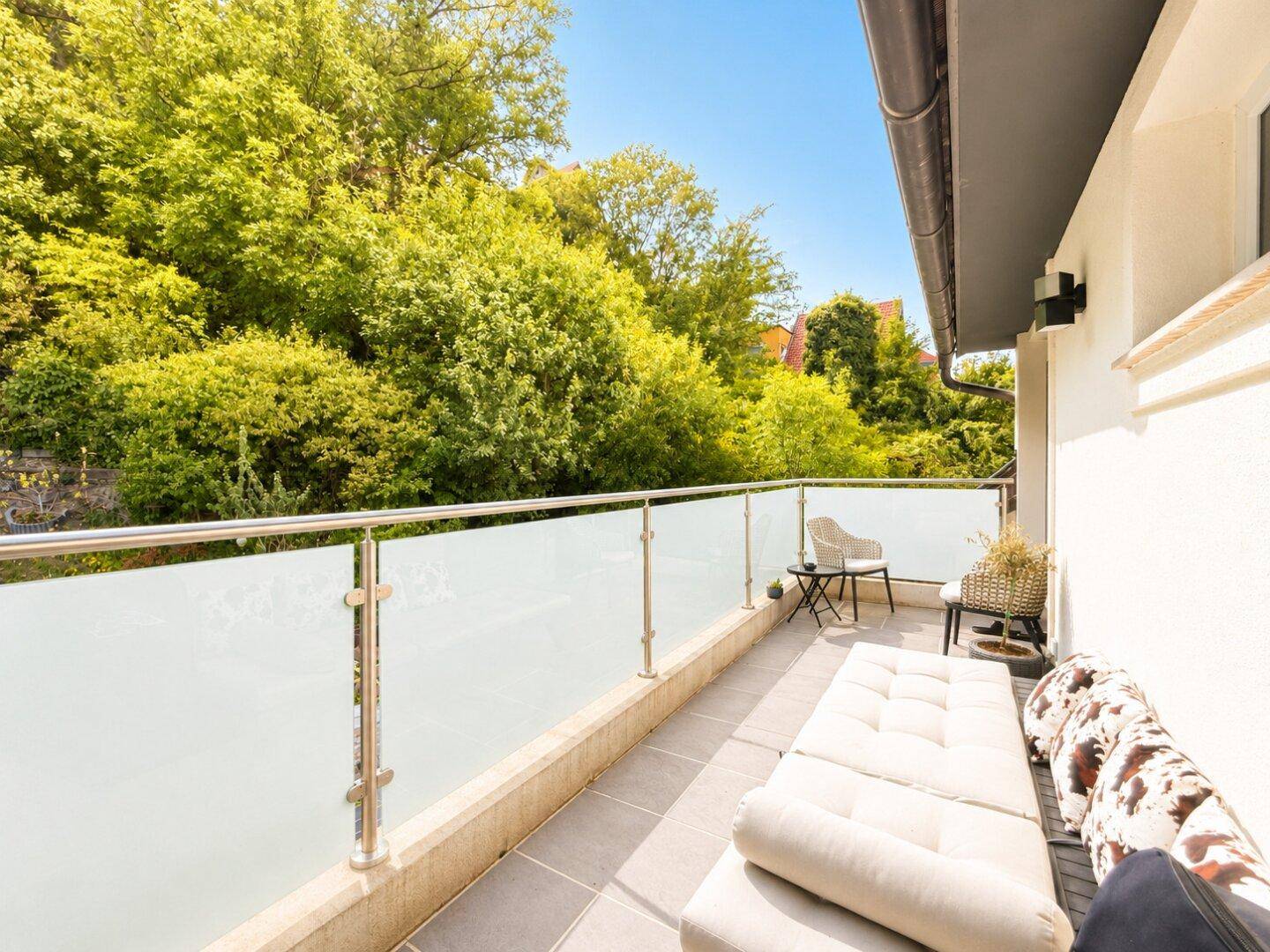 Heller Balkon mit modernen Möbeln und weitem Blick auf die umliegende Natur.