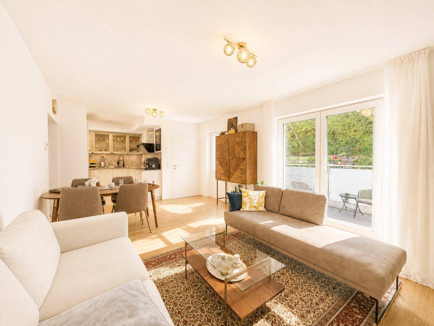 Helles und offenes Wohn-Esszimmer mit Holzboden, Zugang zum Balkon und integrierter Küchenzeile.
