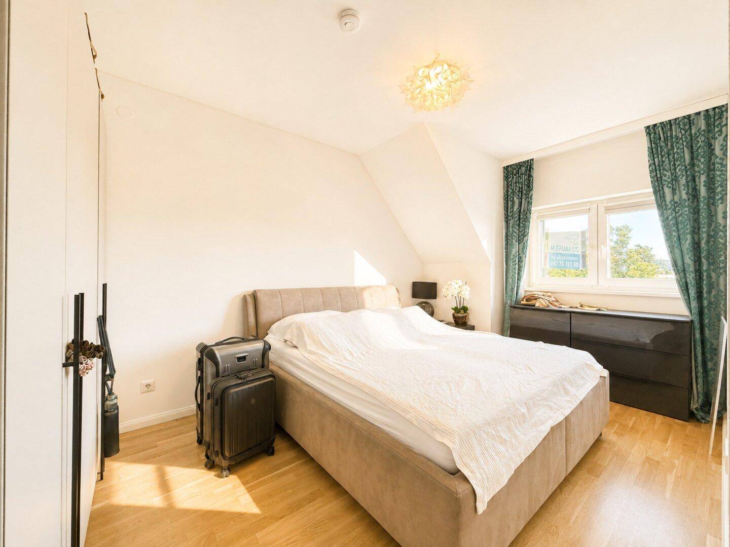 Gemütliches Schlafzimmer mit Doppelbett, Holzboden und Fenster mit Blick ins Grüne.