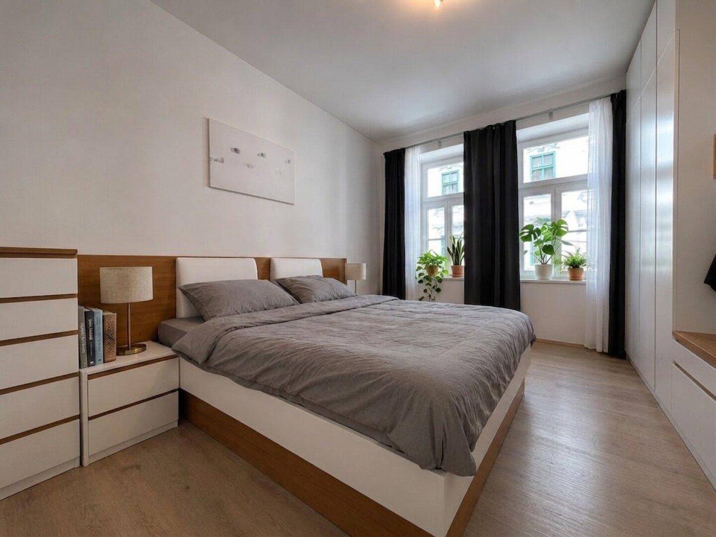 Gemütliches Schlafzimmer mit Doppelbett, Einbauschränken und zwei Fenstern.