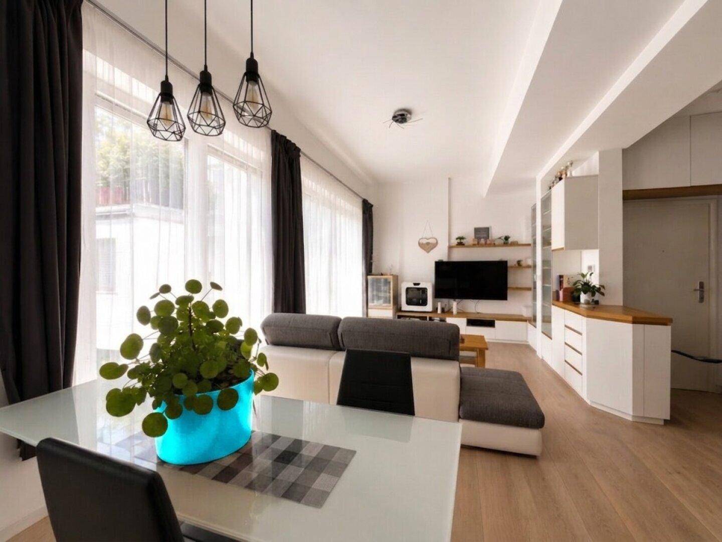 Heller Wohn-Essbereich mit Holzboden, großen Fenstern und modernem Sofa.