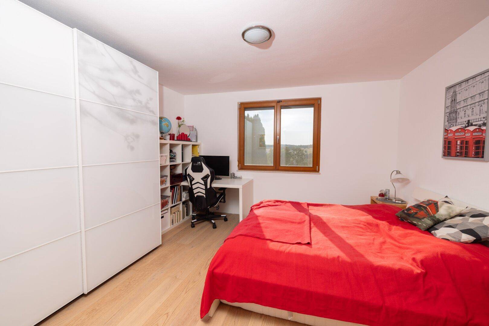 Modern eingerichtetes Schlafzimmer mit hellem Holzboden und großem Kleiderschrank.